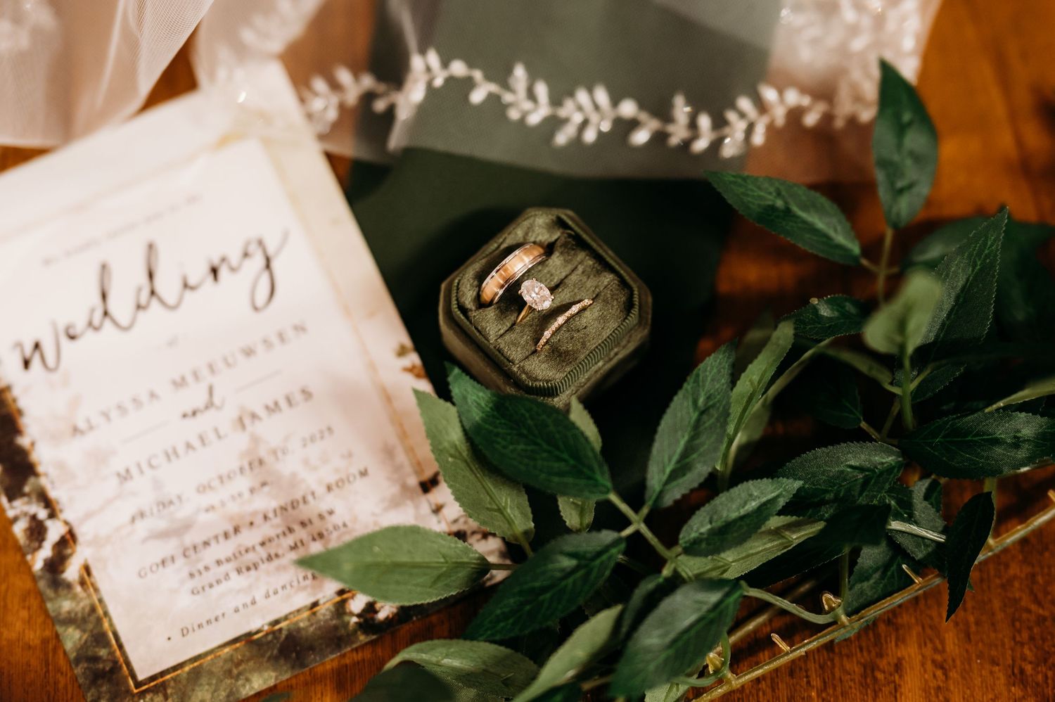 Handwritten letters and green foliage arranged in vintage style on rustic wooden surface in warm lighting.