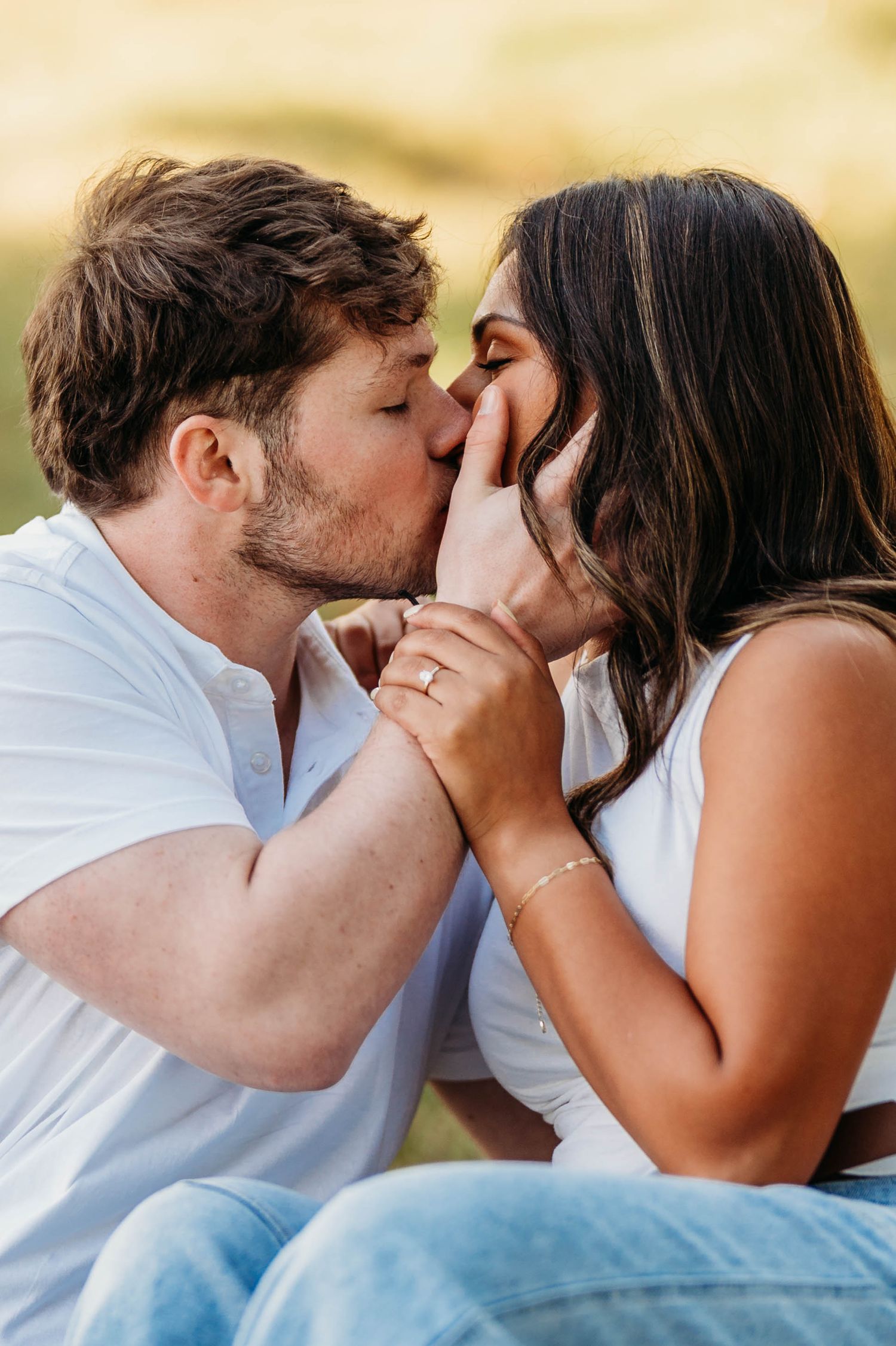 Intimate sequence of a romantic kiss between a couple wearing white and denim in warm sunlight.
