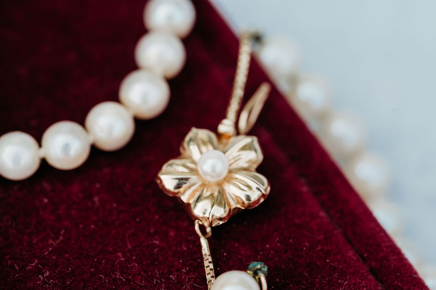 Pearl and gold butterfly jewelry pieces displayed on dark red velvet fabric background.