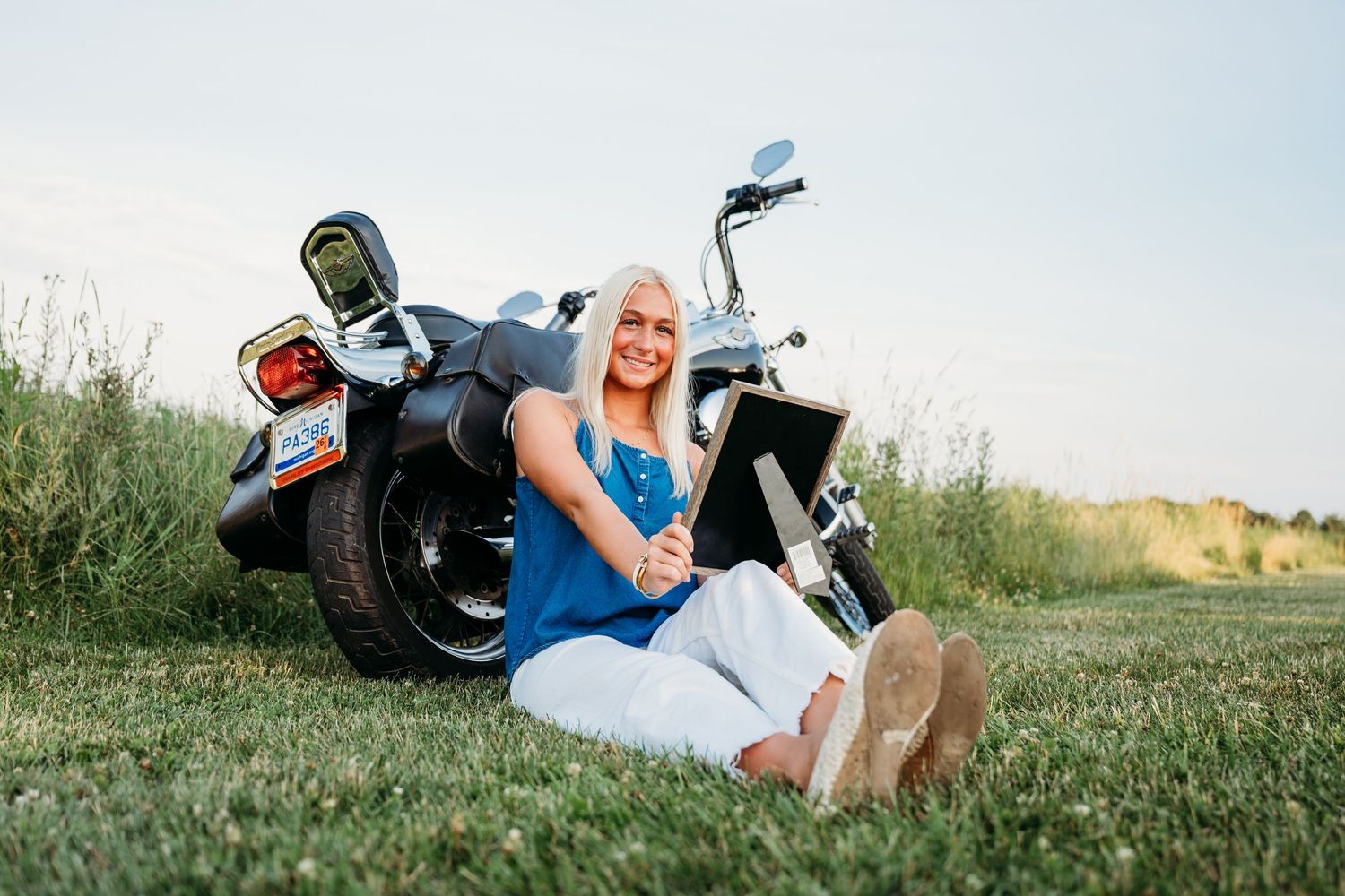 A sequence of six progressive shots showing a person in casual clothing rolling down a grassy hill in summer.