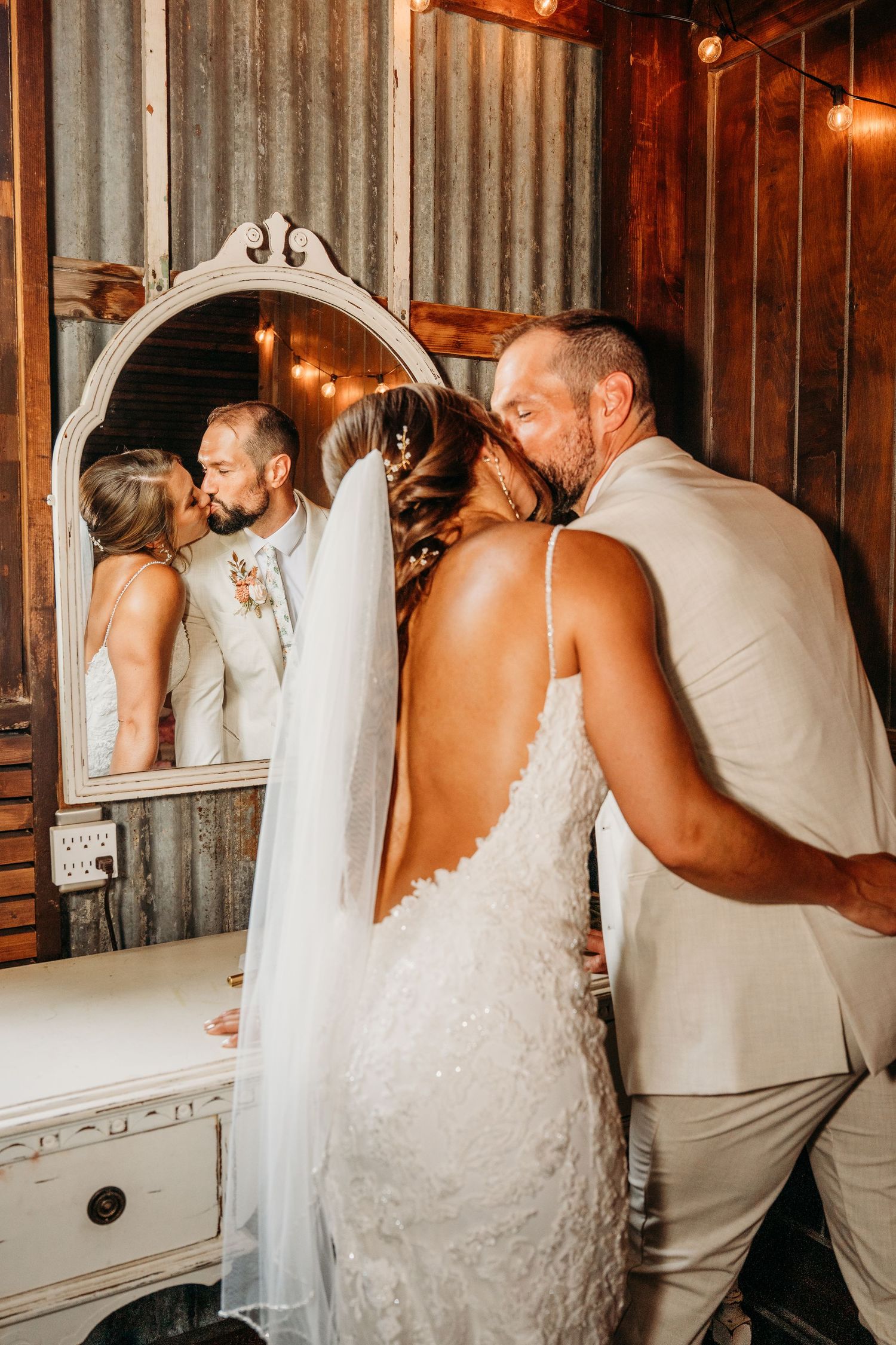 Couple sharing intimate dance moment in rustic barn setting with white vintage mirror.