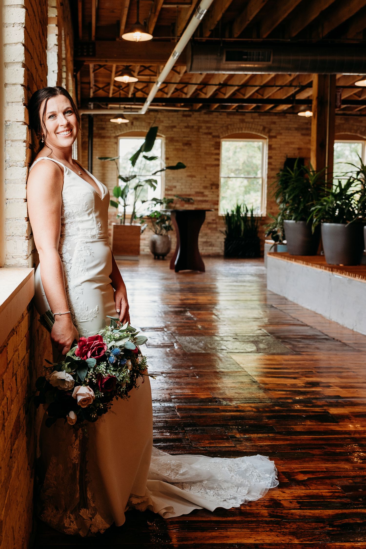 Rustic industrial venue interior with exposed brick walls, wooden floors and natural light streaming through windows.