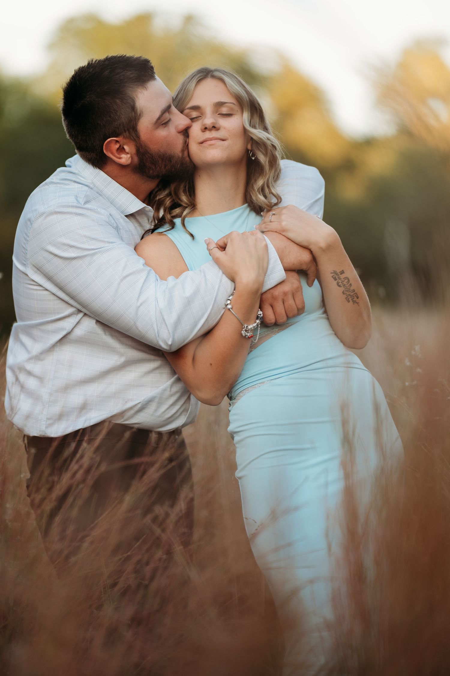 A romantic couple embraces in a field during golden hour as they share intimate kisses in a series of candid moments.