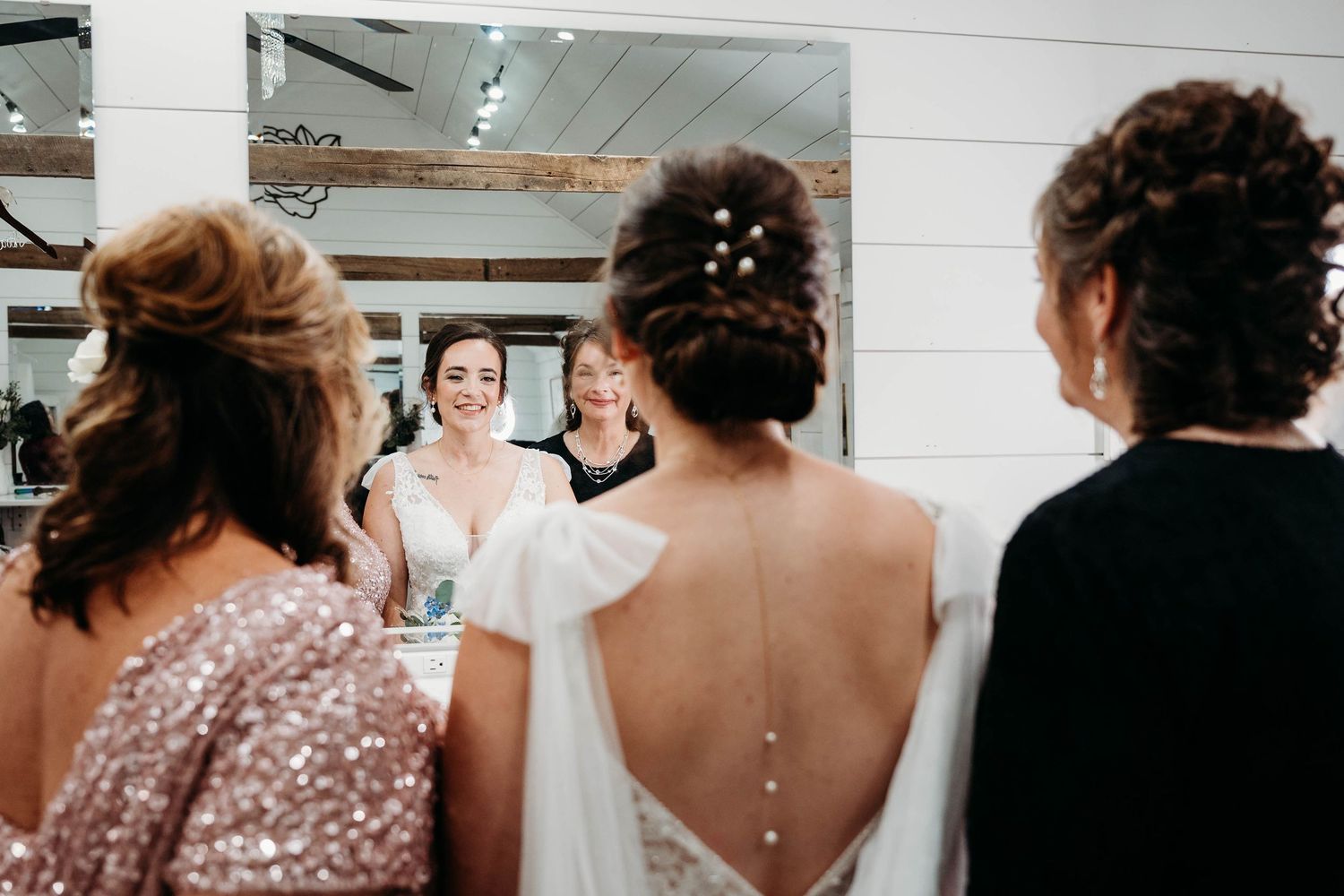 Wedding party members gather around a mirror in a bridal suite as they prepare for the ceremony.