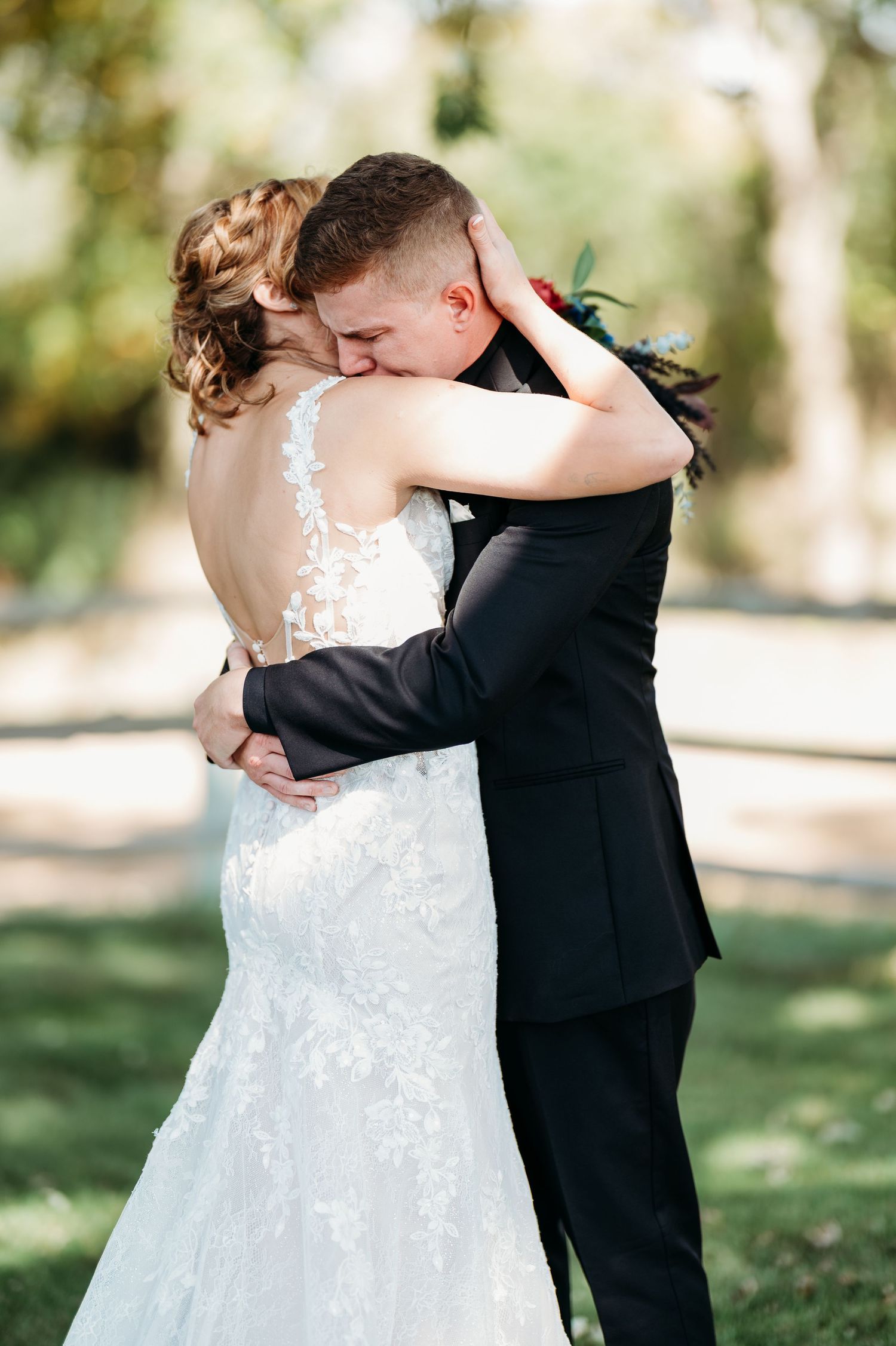 A romantic wedding moment captured in a garden setting as a couple in formal attire embrace.