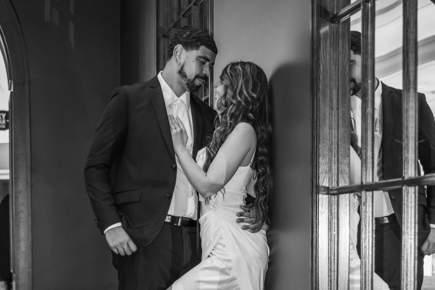 A series of romantic wedding photos in black and white showing couples embracing in a hallway corridor.