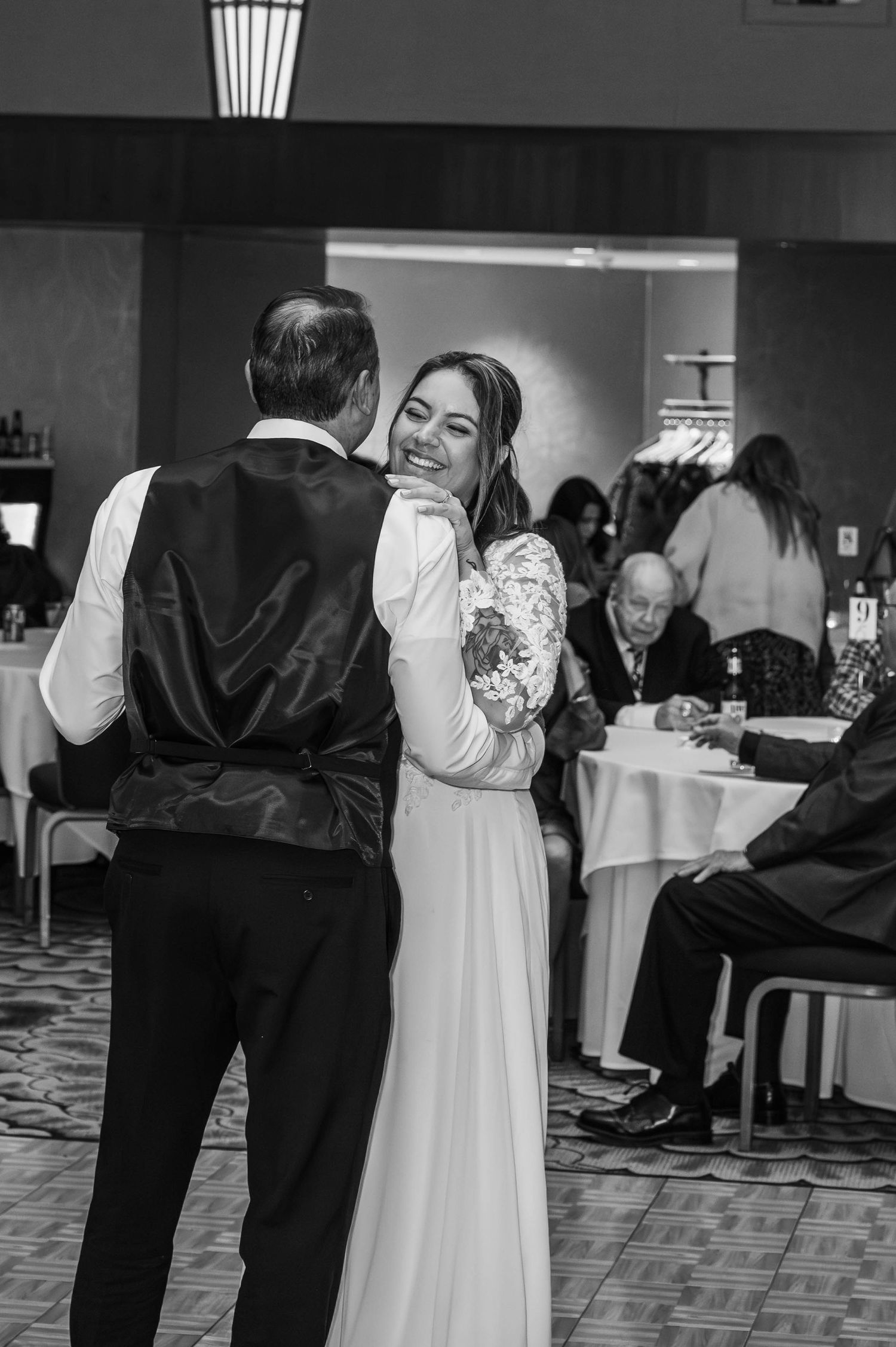 A couple shares a romantic dance moment in a reception hall with black and white decor.
