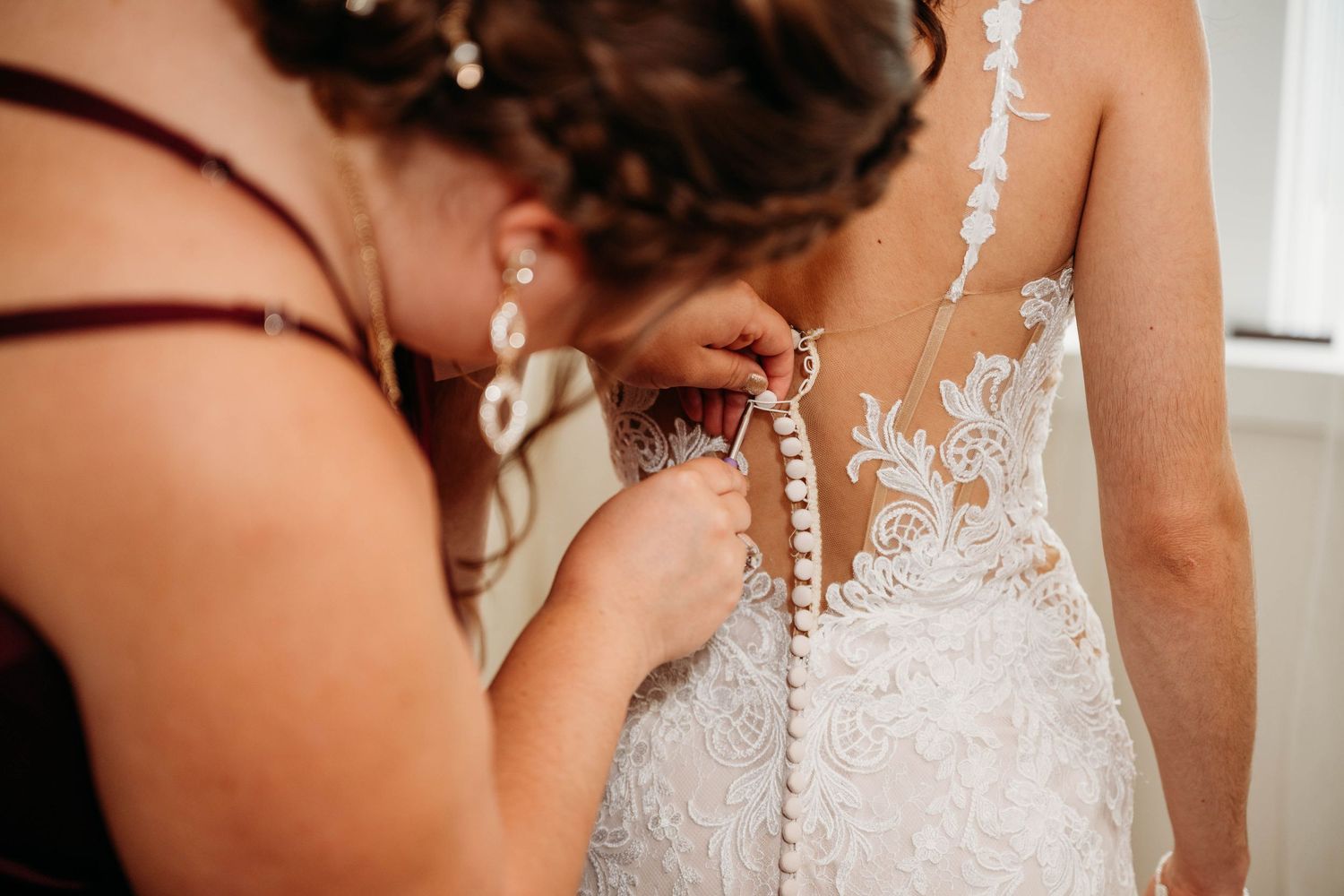 A close-up detail shot of delicate white lace buttons on the back of a wedding dress.