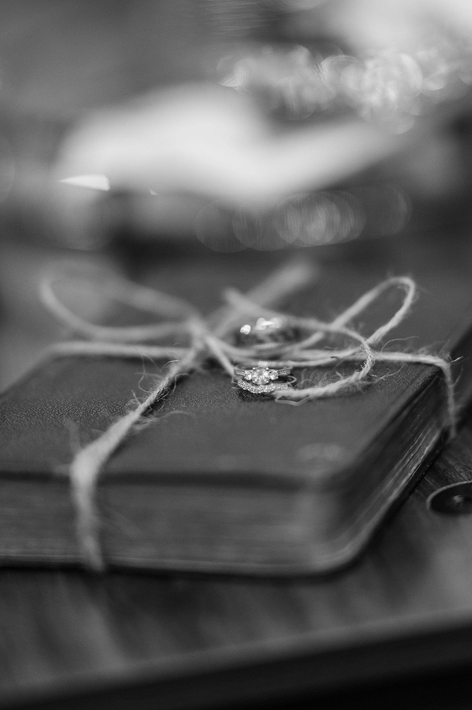 Sparkling diamond engagement ring rests on a dark leather surface with shallow depth of field.
