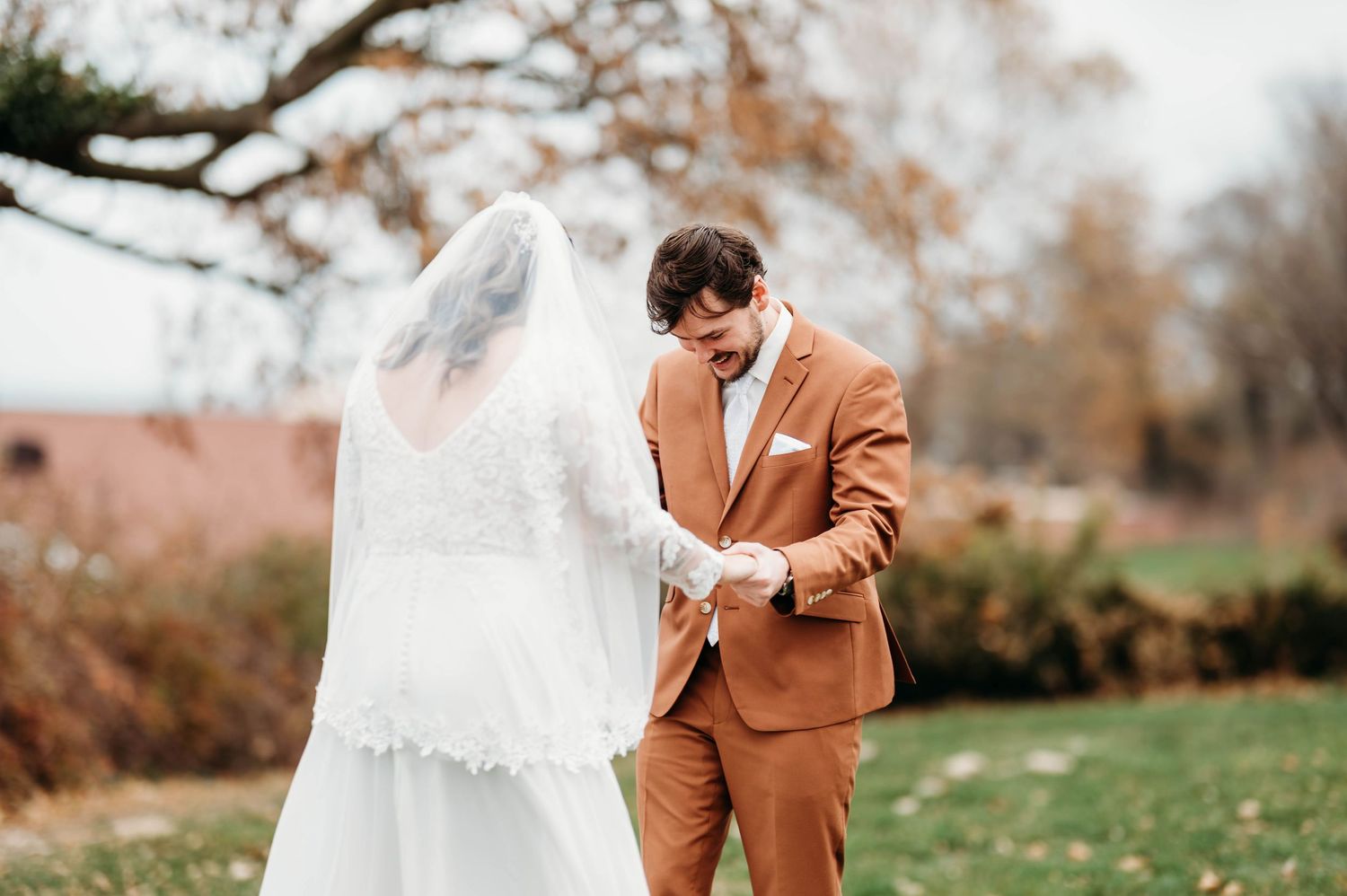 Couple shares emotional first look moment in an autumn outdoor setting with fall foliage in background.