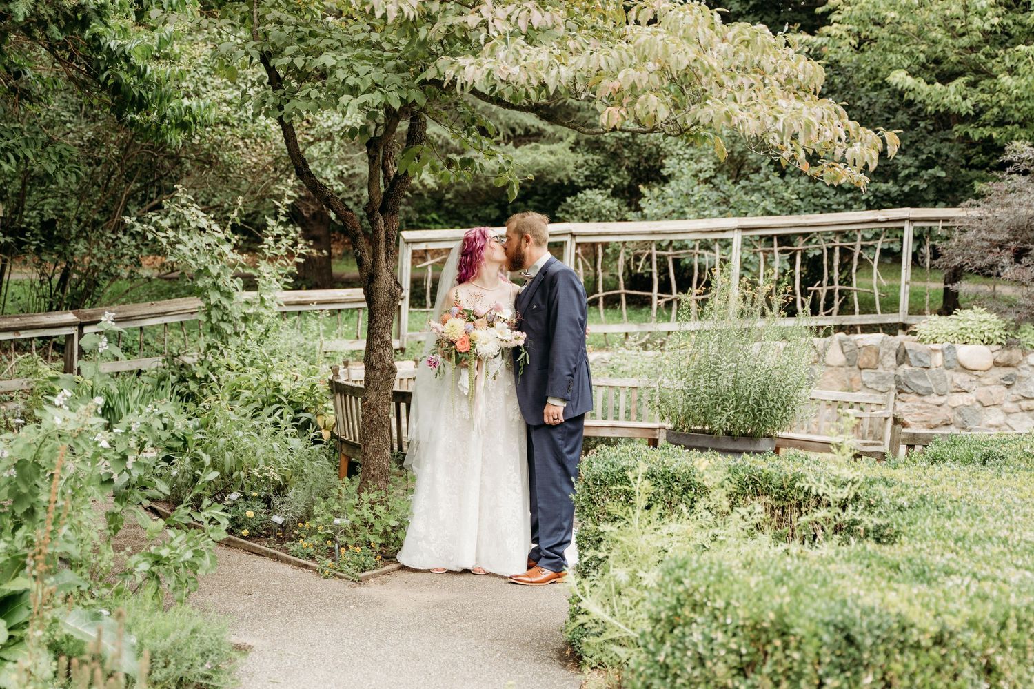 Couple sharing an intimate moment in a lush garden setting with greenery and natural surroundings.