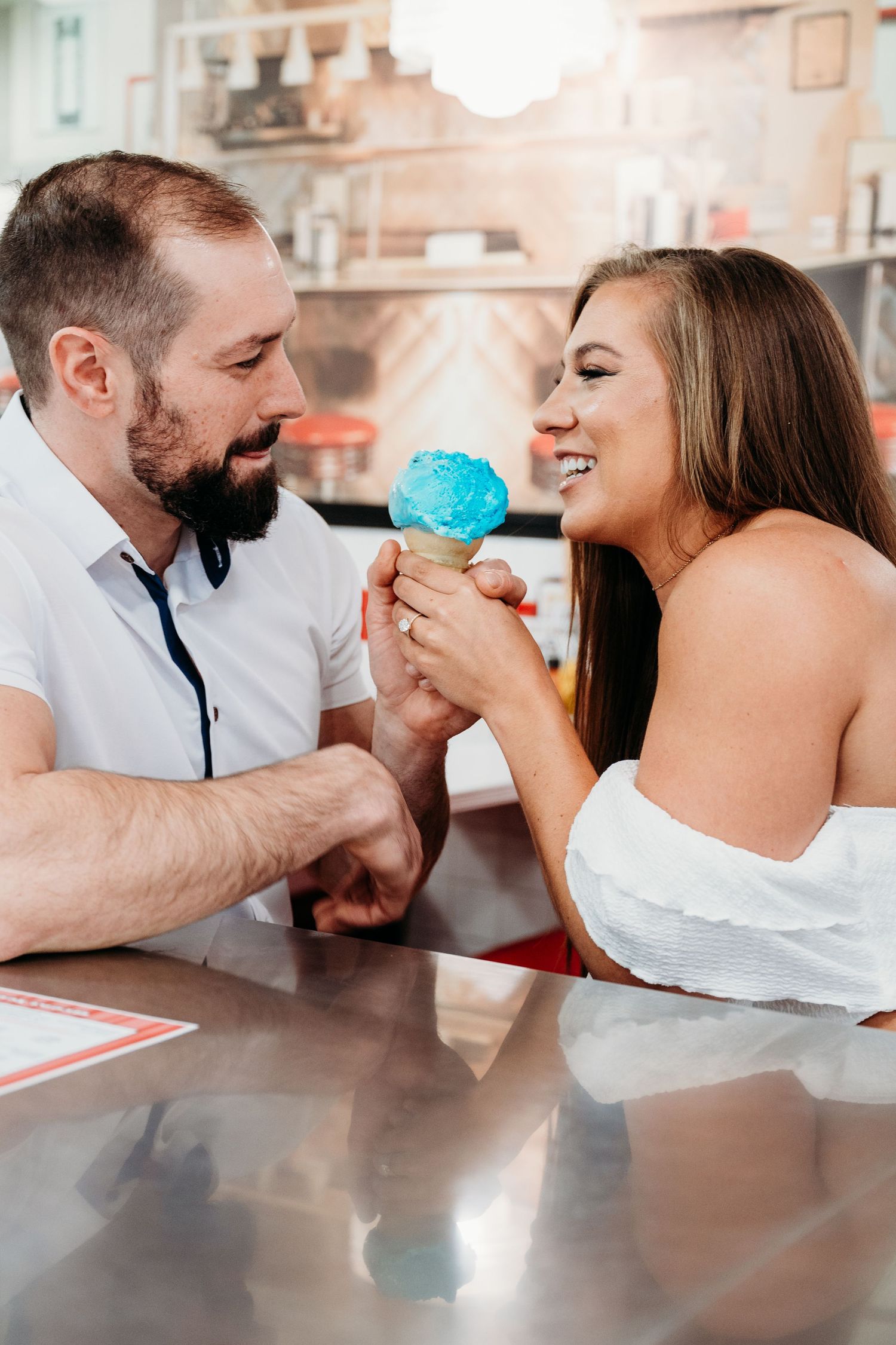 A couple shares a sweet moment at an ice cream parlor while enjoying a bright blue ice cream cone together.