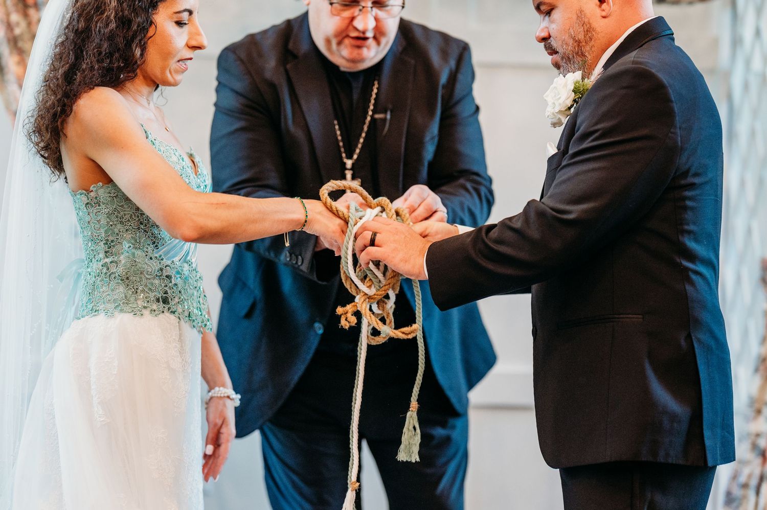 Bride and groom participate in a rope handfasting ceremony with officiant during their wedding.