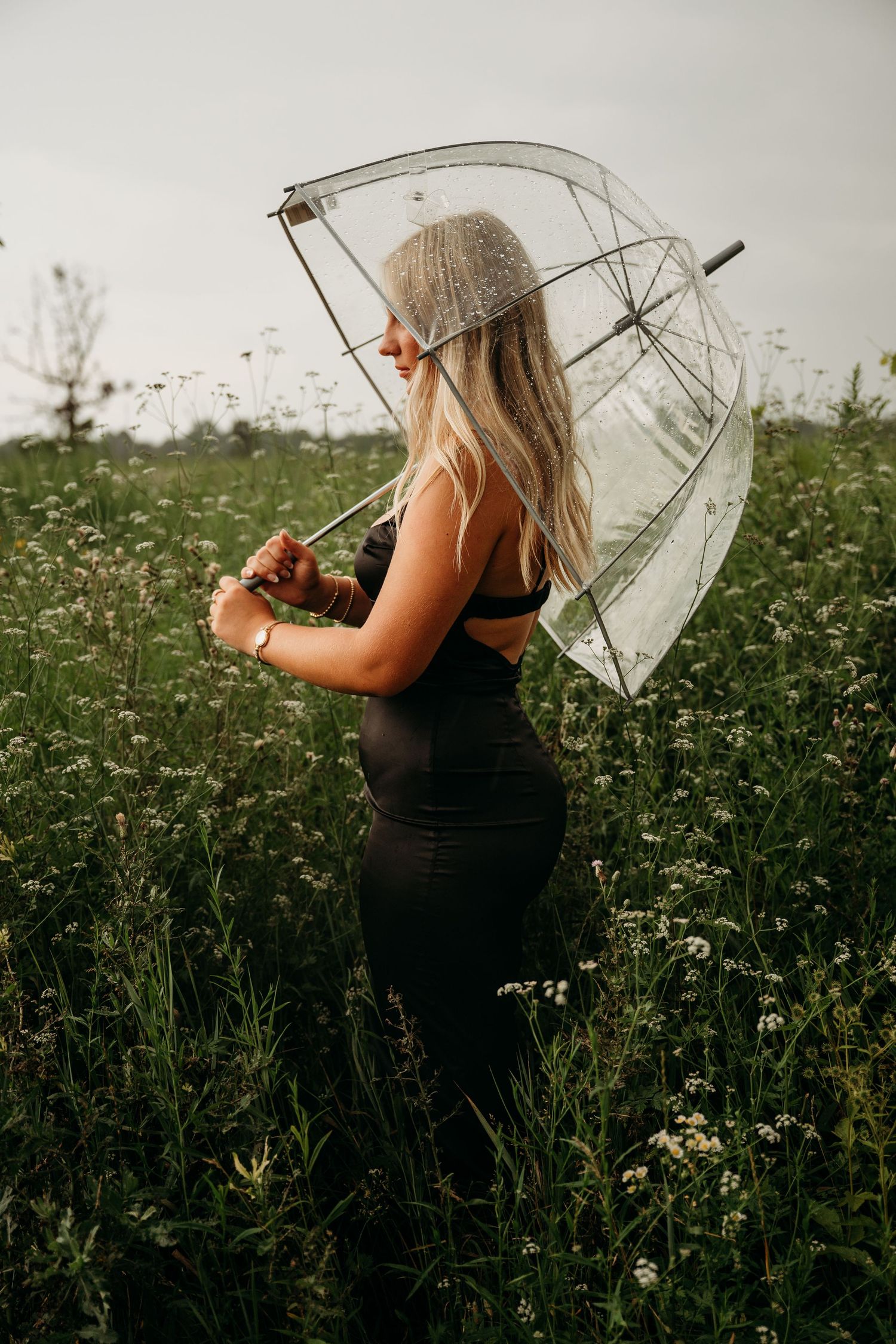 A sequence of shots showing someone in a black dress with a clear umbrella in a field of wildflowers.