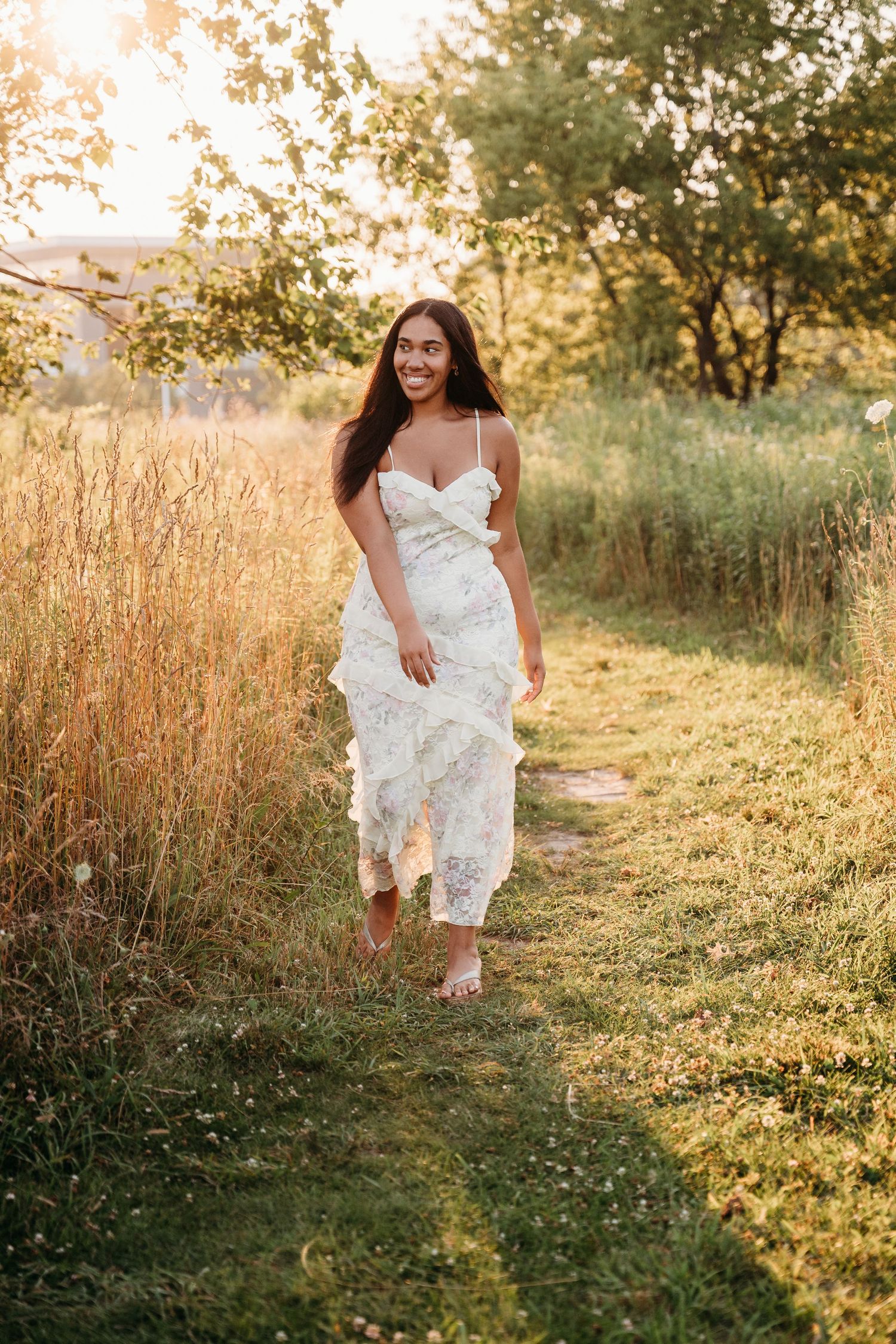 Summer wedding photos show a person in a flowing white dress running through tall golden grass at sunset.
