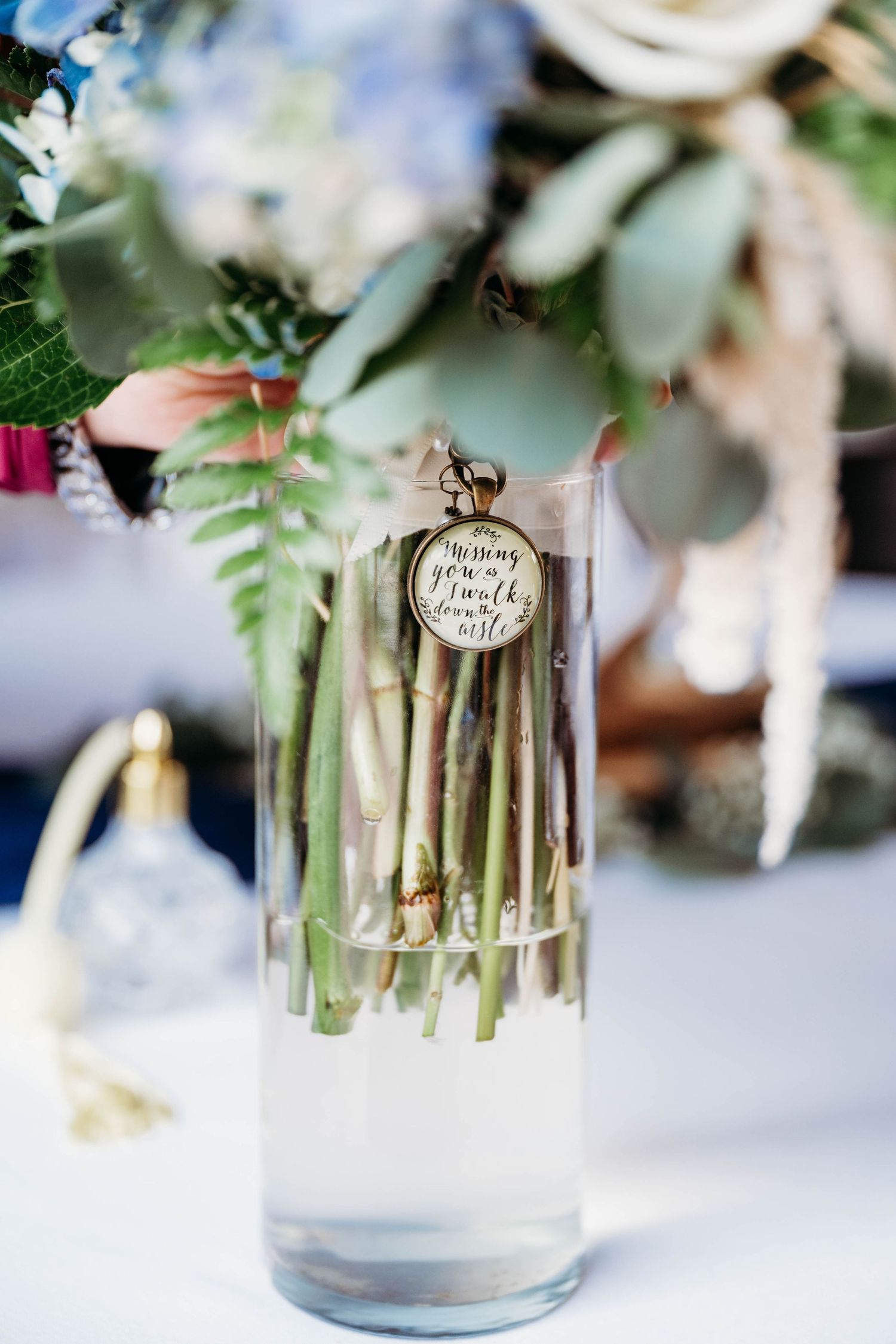 Delicate floral centerpieces in glass vases with personalized name tags on display at wedding reception.