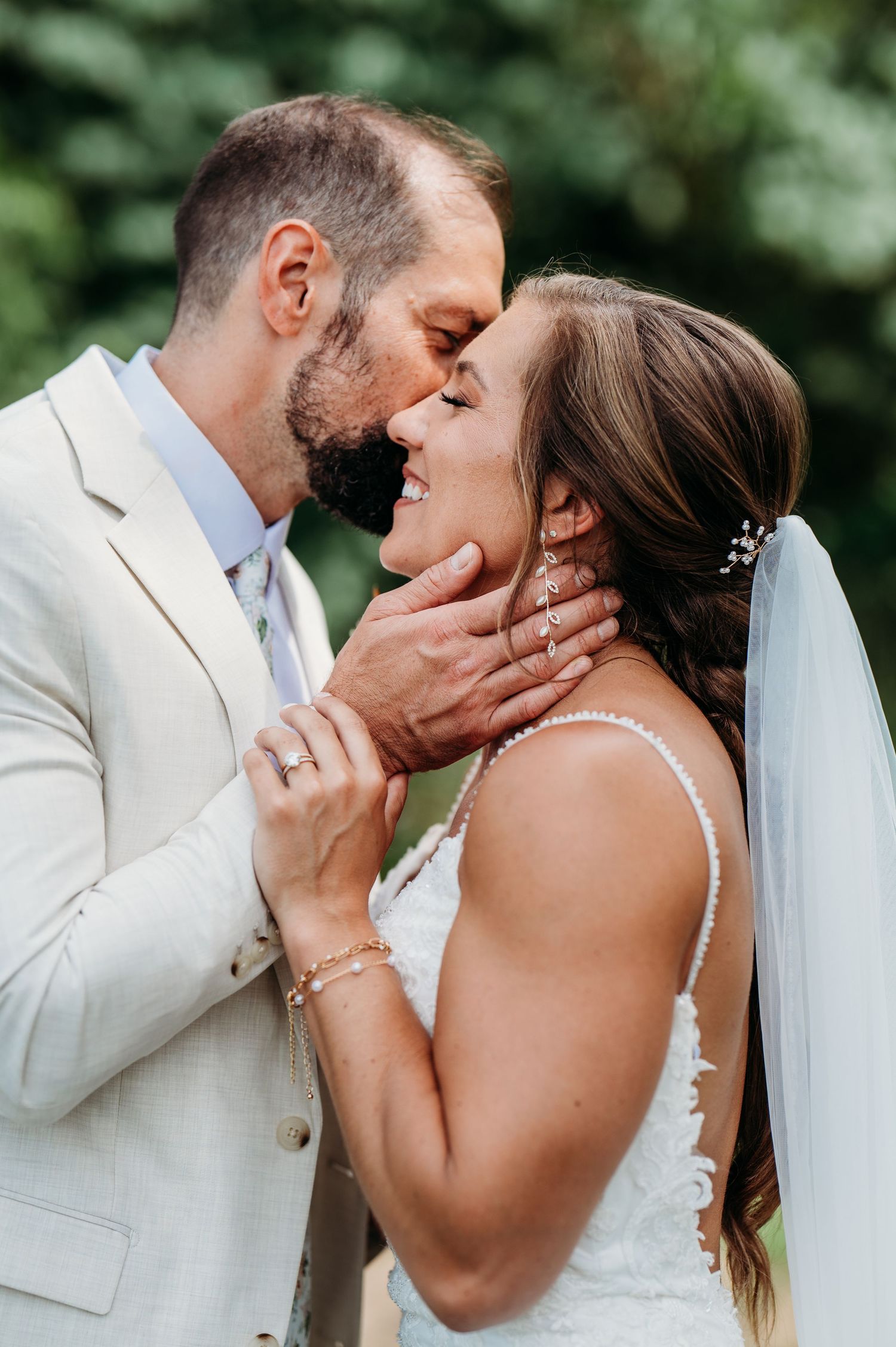 A romantic wedding kiss sequence showing tender moments between newlyweds in white attire against a natural backdrop.