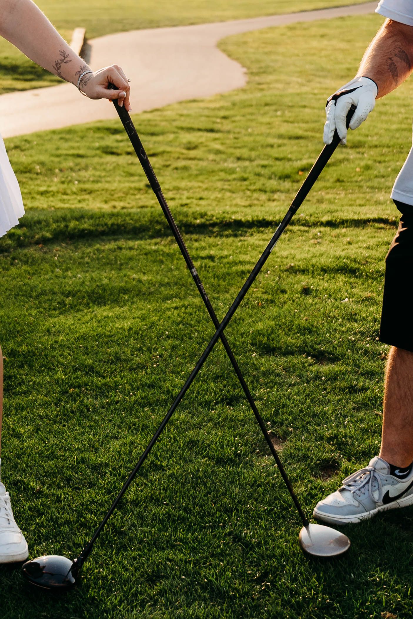 Close-up view of golfers' legs and clubs on a lush green golf course during practice.