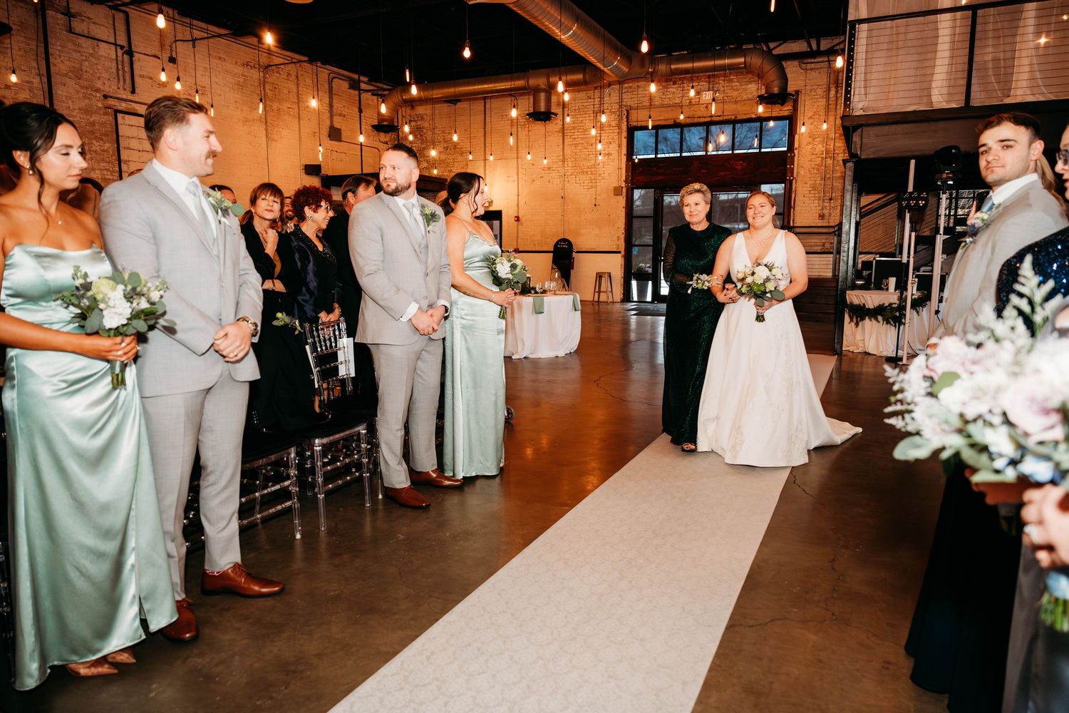 Wedding ceremony in a rustic industrial venue with mint green bridesmaid dresses and gray suits.
