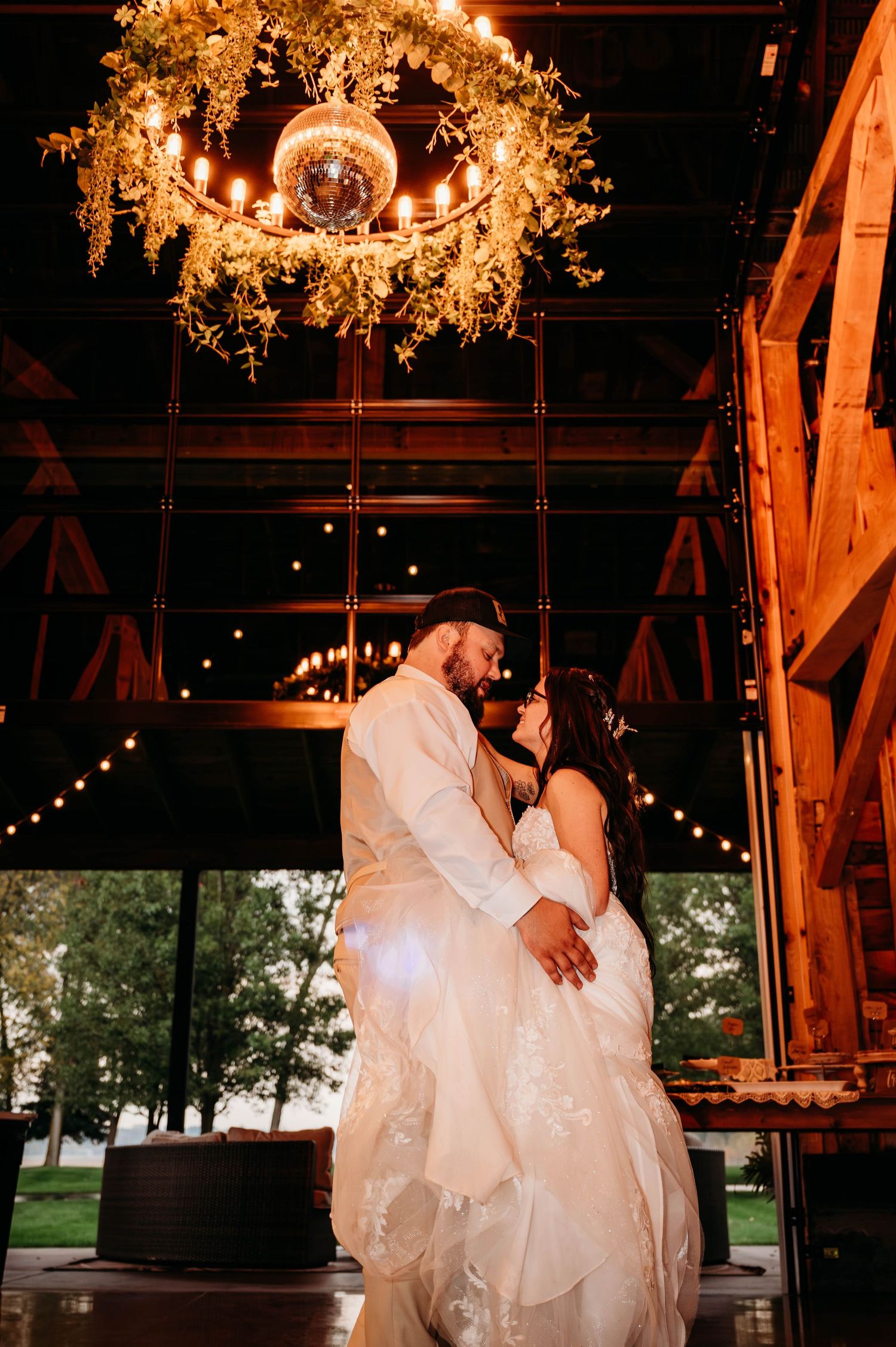 Romantic dance sequence in a rustic barn venue illuminated by warm string lights.