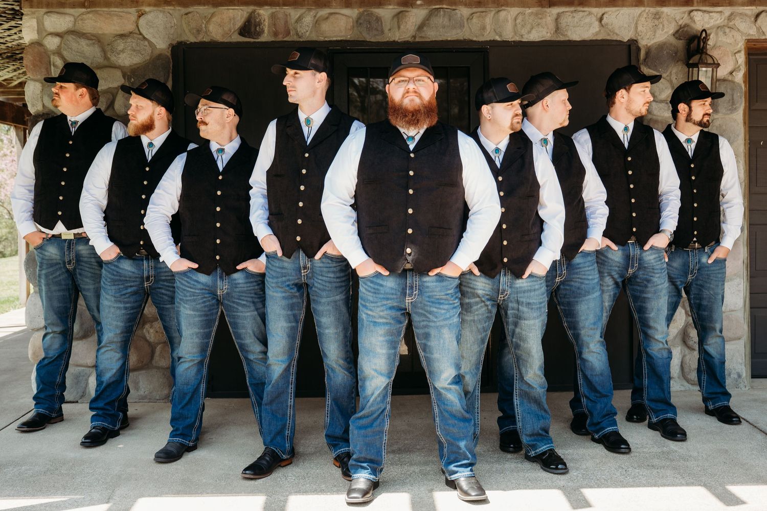 Groomsmen wearing matching black shirts and blue jeans pose for a creative photograph showing just their lower halves.