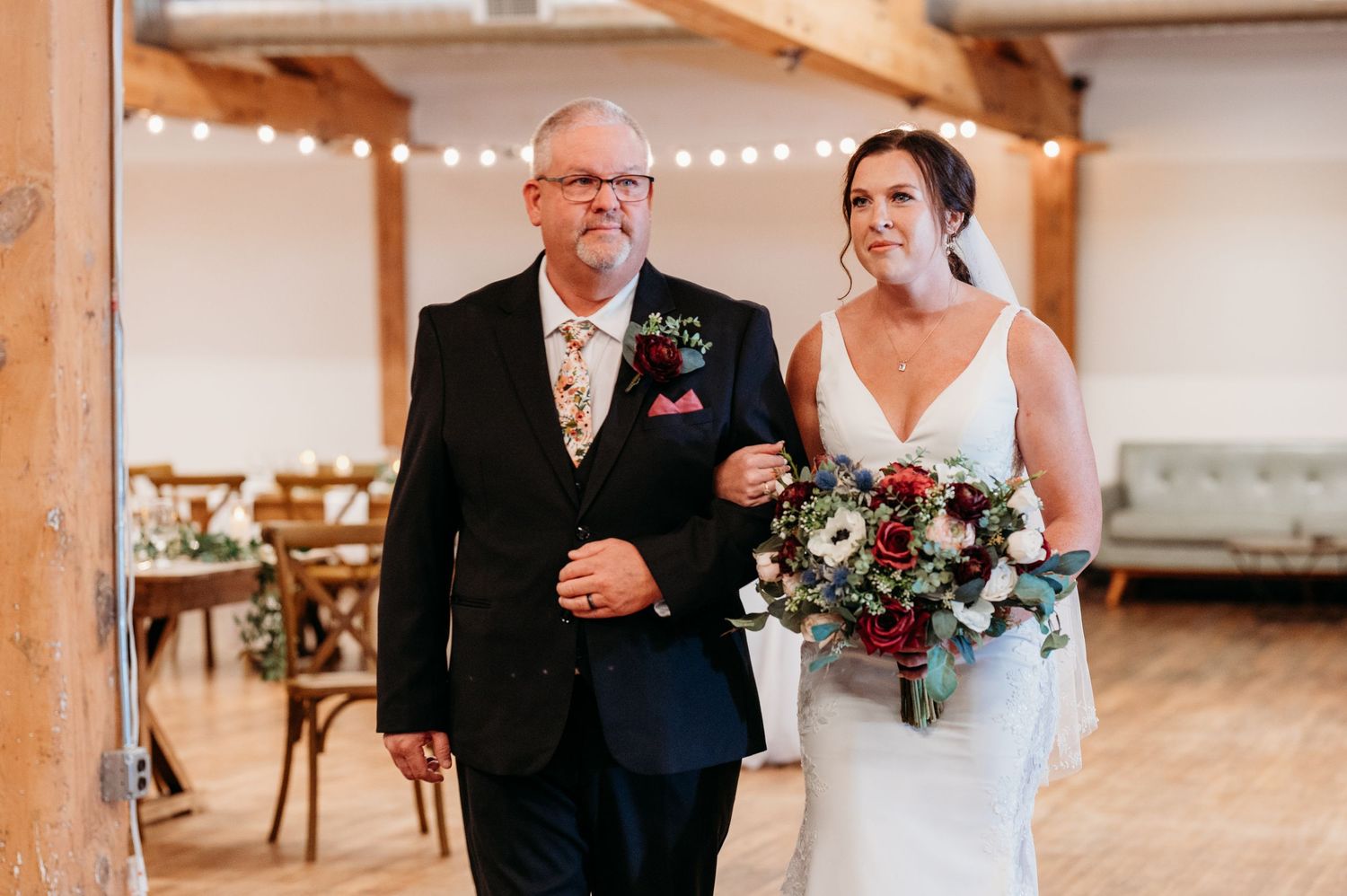 Wedding party lineup in front of exposed brick wall with wooden beams and string lights.