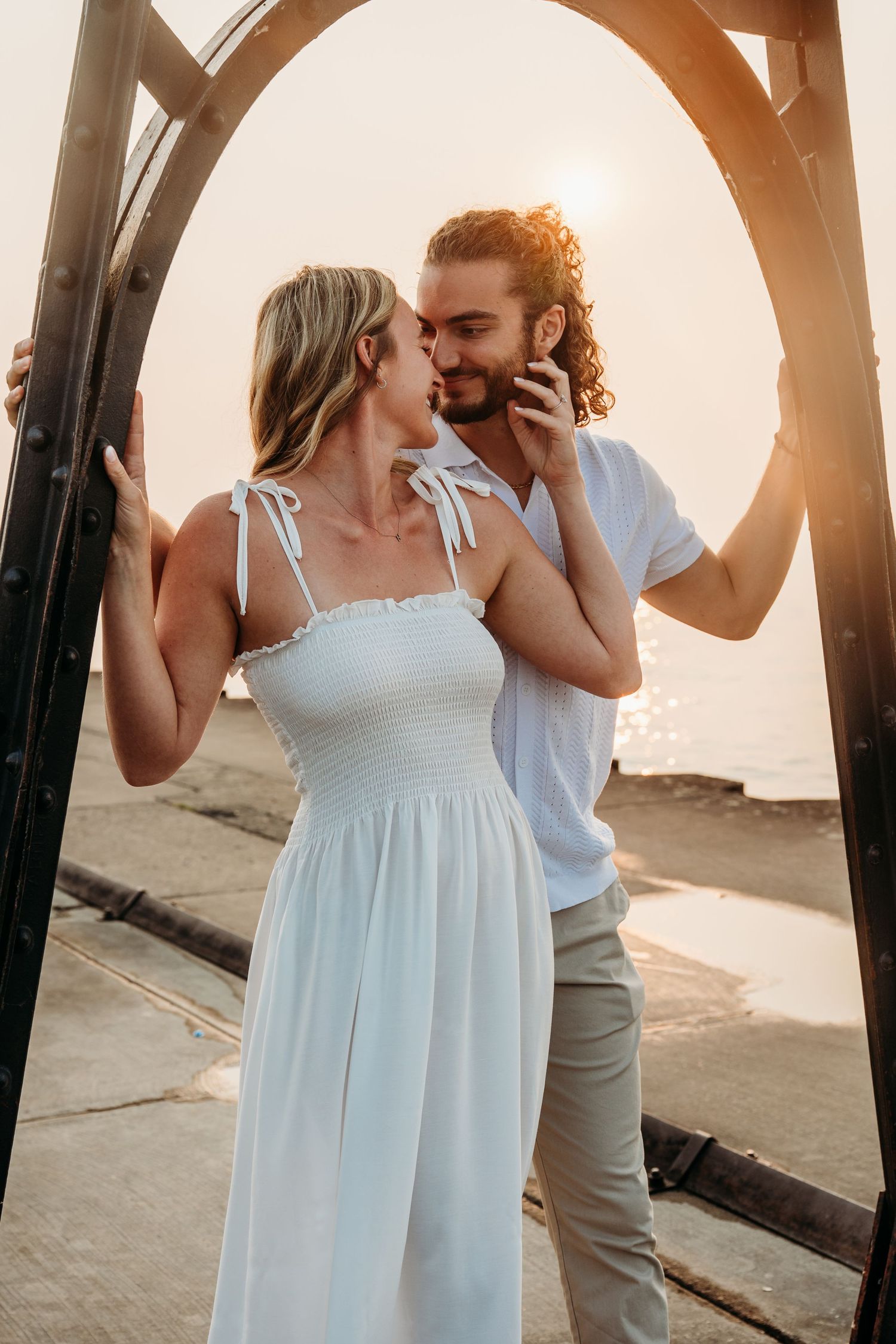 A romantic couple kissing under an archway at sunset.