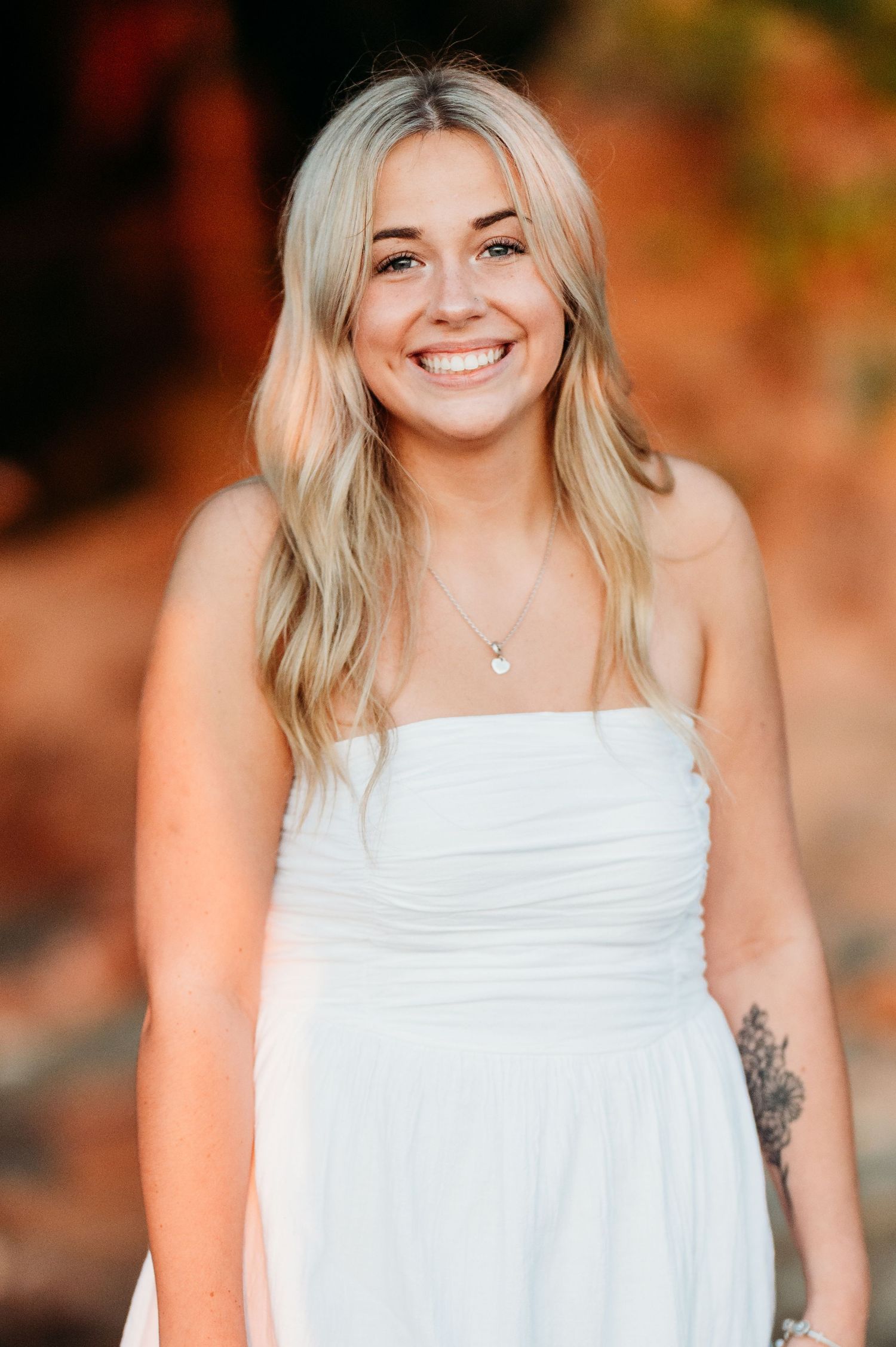 A warm sunset portrait featuring a strapless white dress against a glowing orange background.