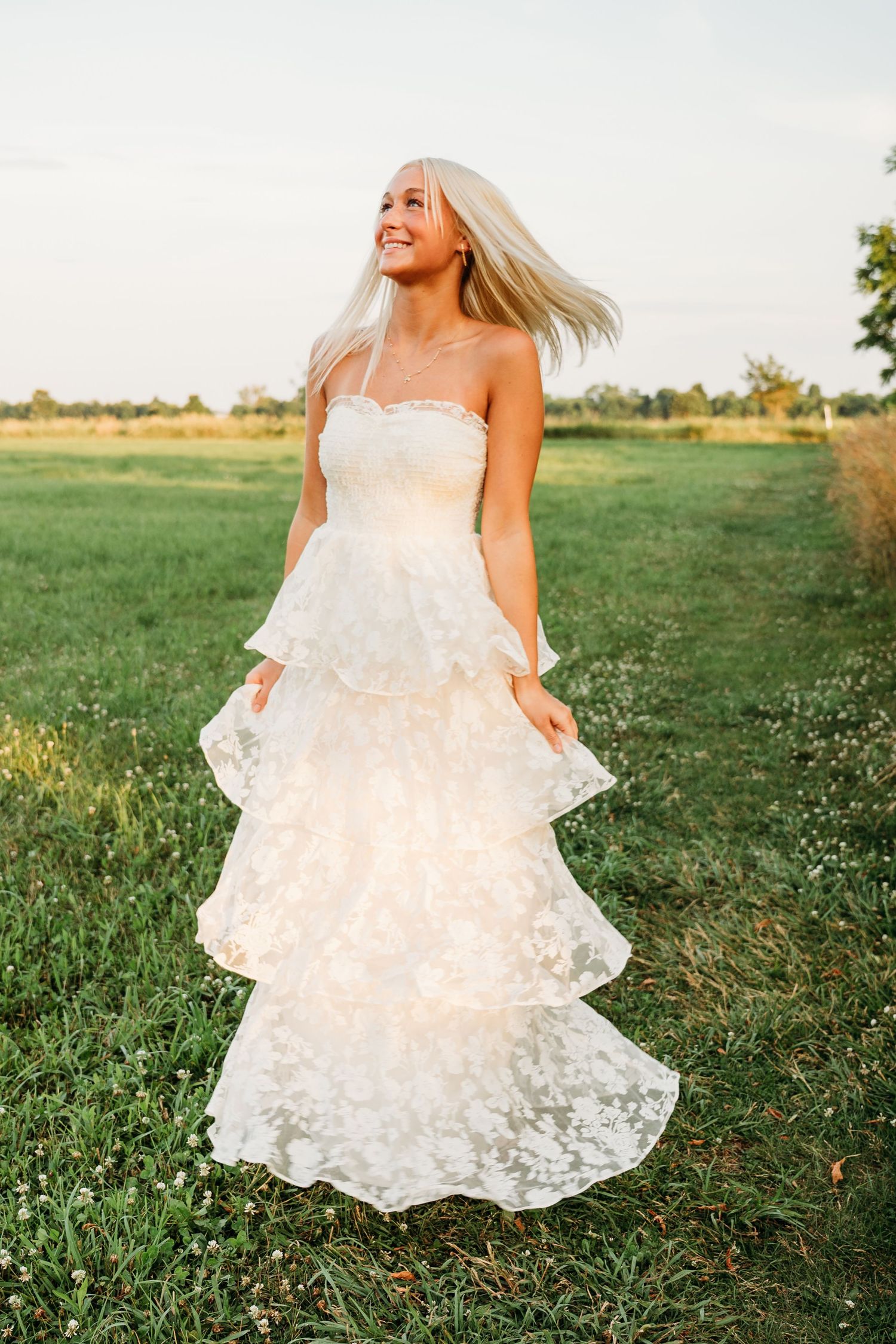 Ethereal photos capture flowing white lace dress twirling in a sunlit meadow with wildflowers.