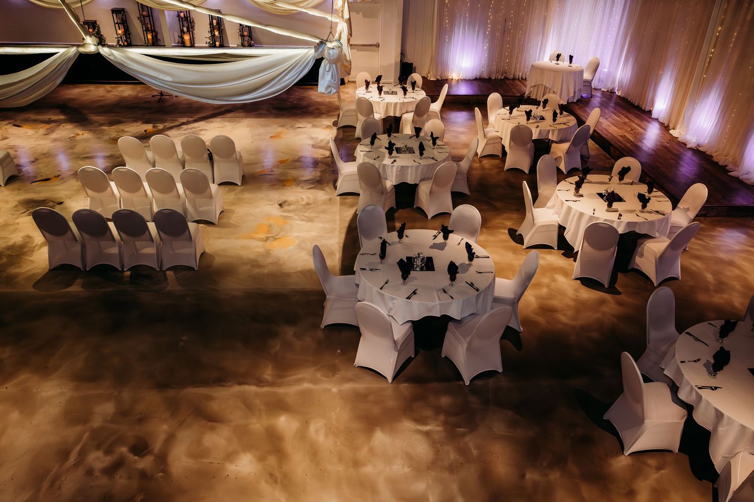 Elegant wedding reception venue with white chair covers and warm ambient lighting creating a romantic atmosphere.