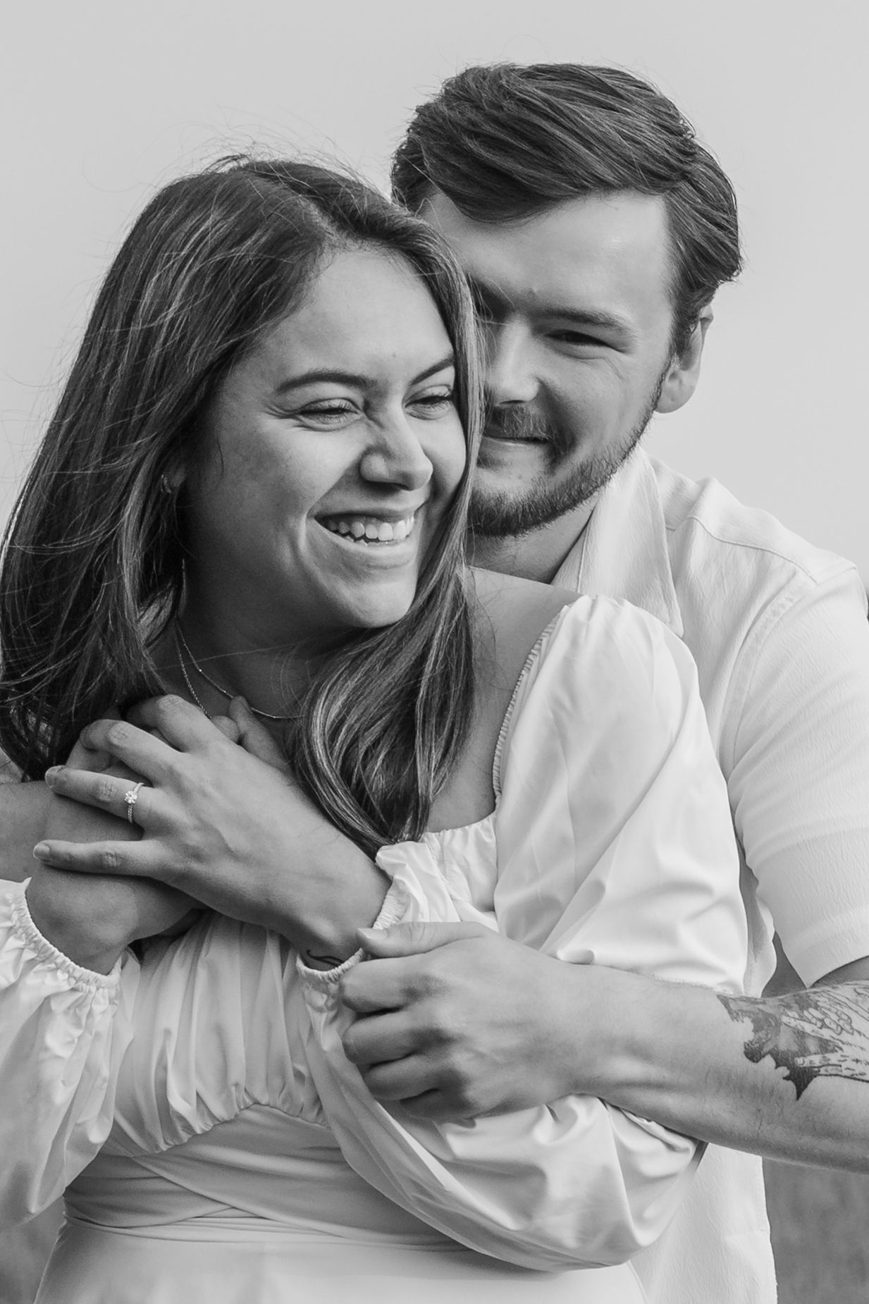 Series of black and white photos showing a couple laughing and embracing while wearing white clothing.