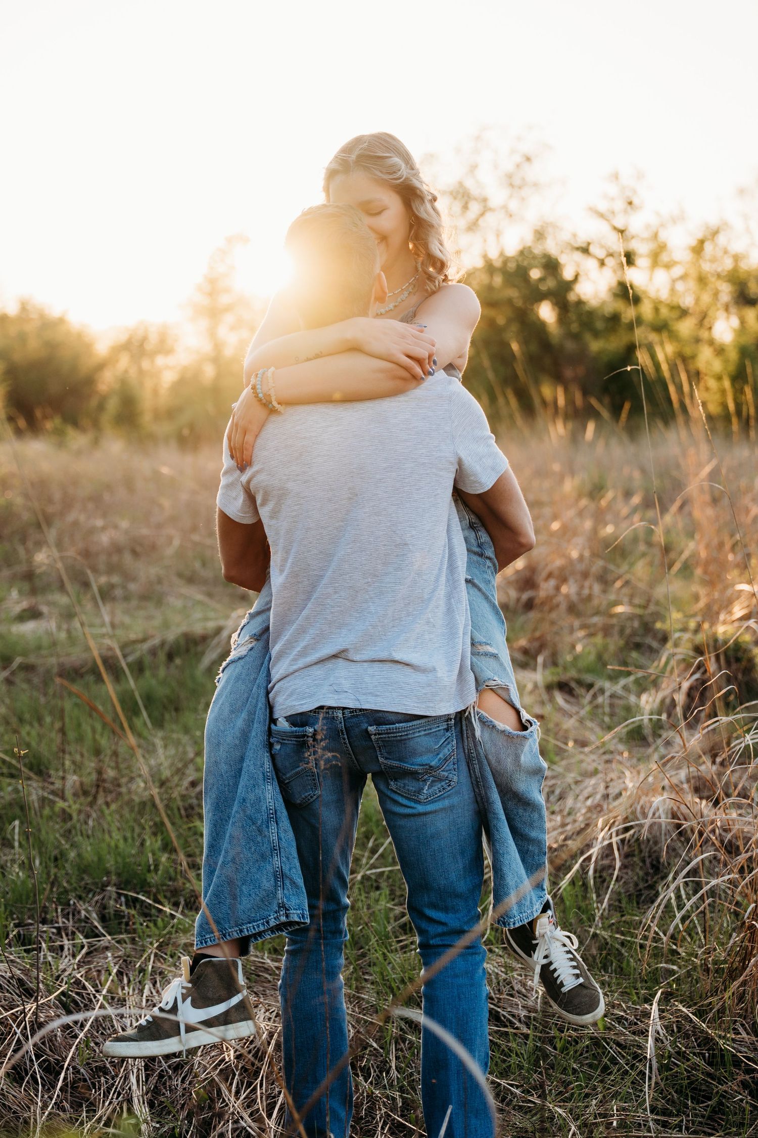 People walking together in a sunlit field during golden hour, wearing casual denim and t-shirts.