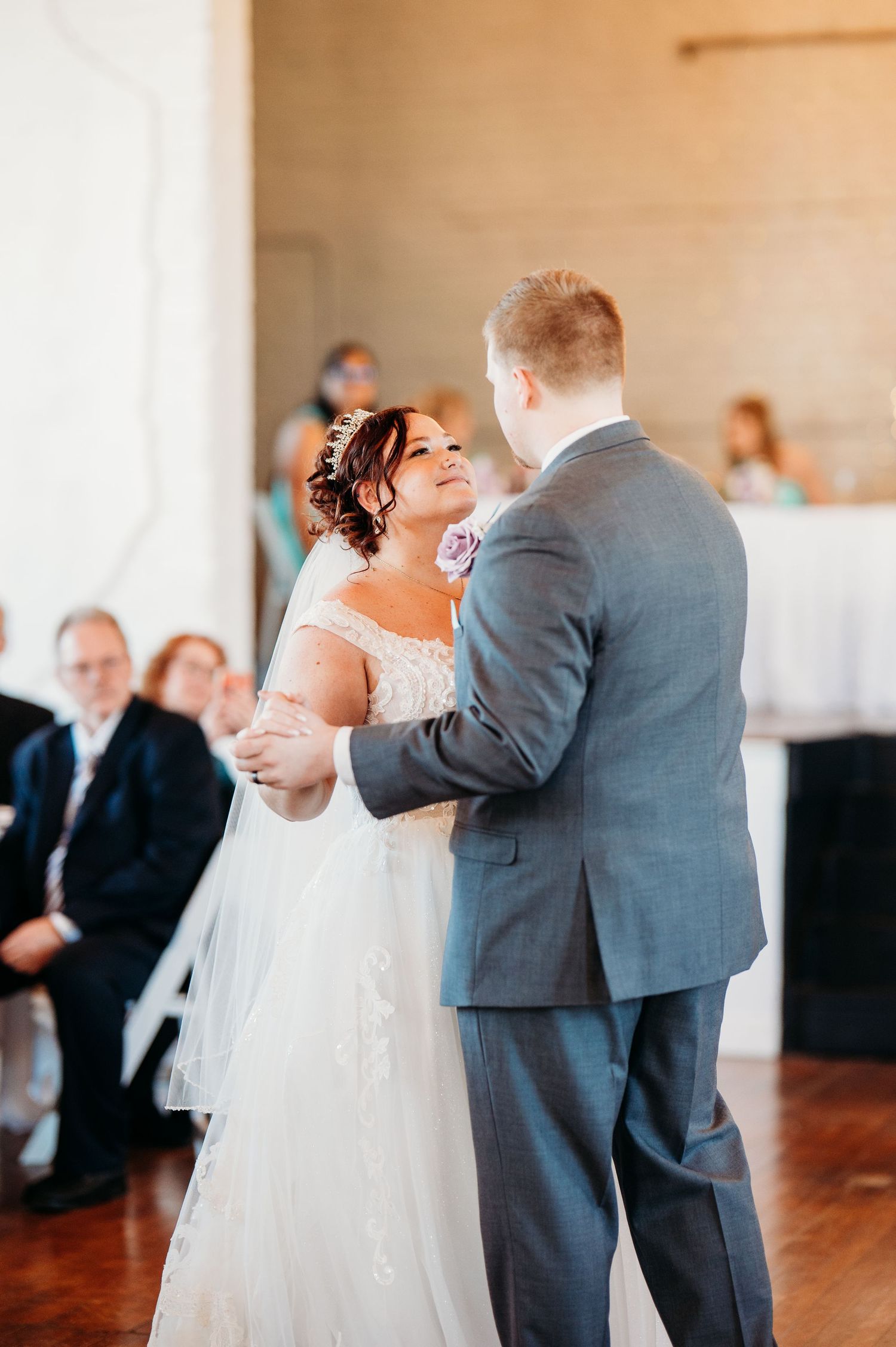 A couple shares their first dance at their wedding reception while guests look on.