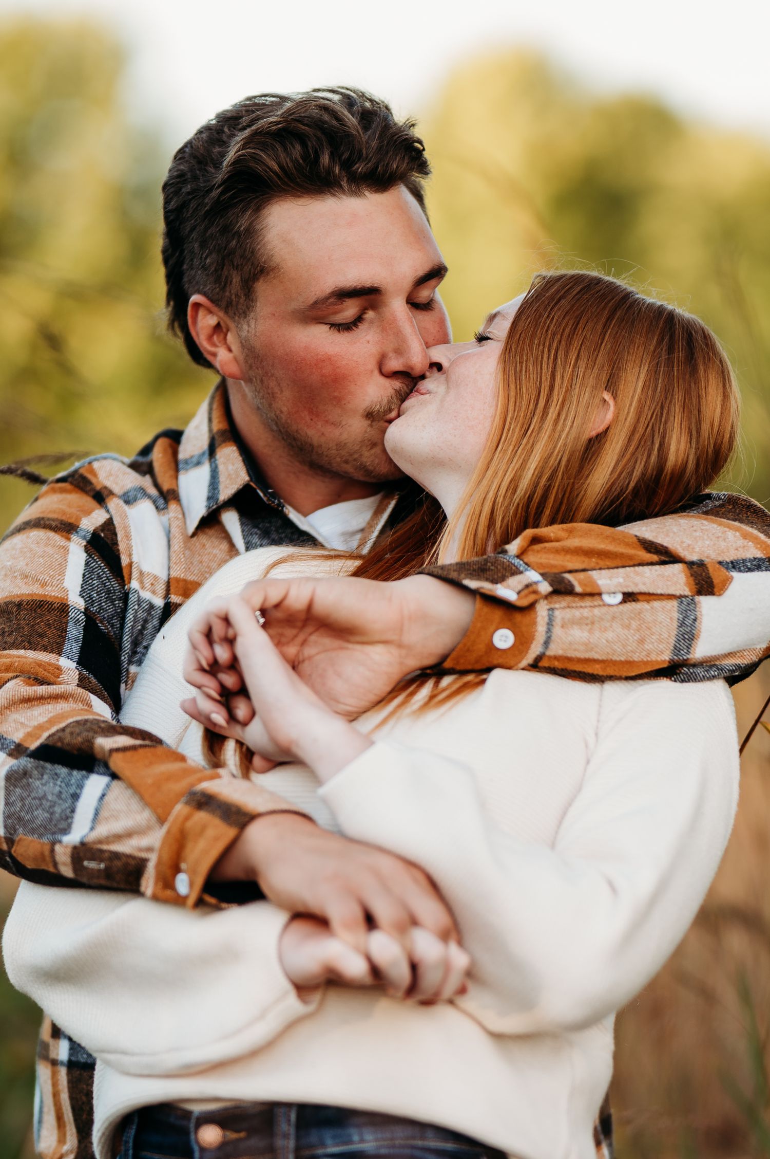 A couple in casual attire embraces and kisses in a romantic outdoor photoshoot sequence.
