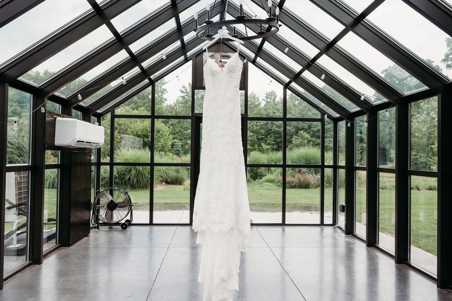 Modern greenhouse interior with glass ceiling and white pillars creates bright, airy wedding ceremony space.