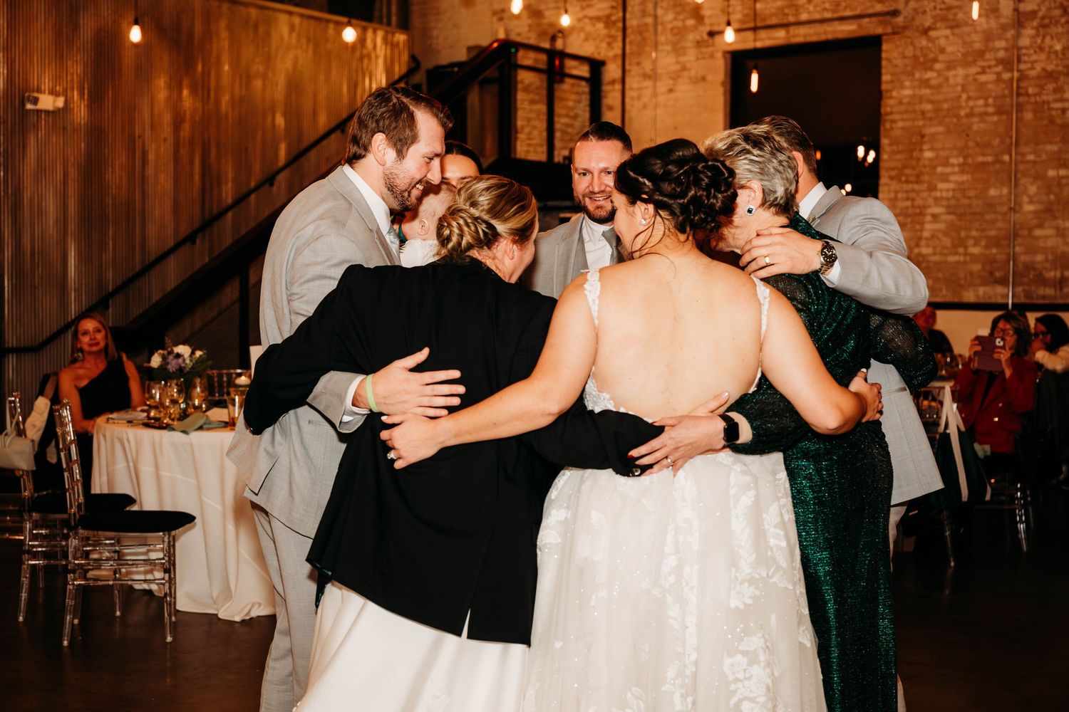 Wedding reception dance floor with guests celebrating in dimly lit rustic venue.