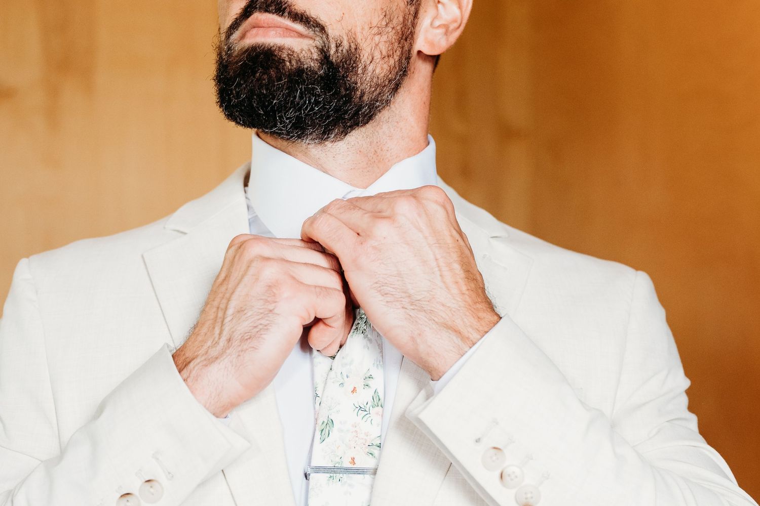 A close-up view of a white bowtie being adjusted on a formal dress shirt.