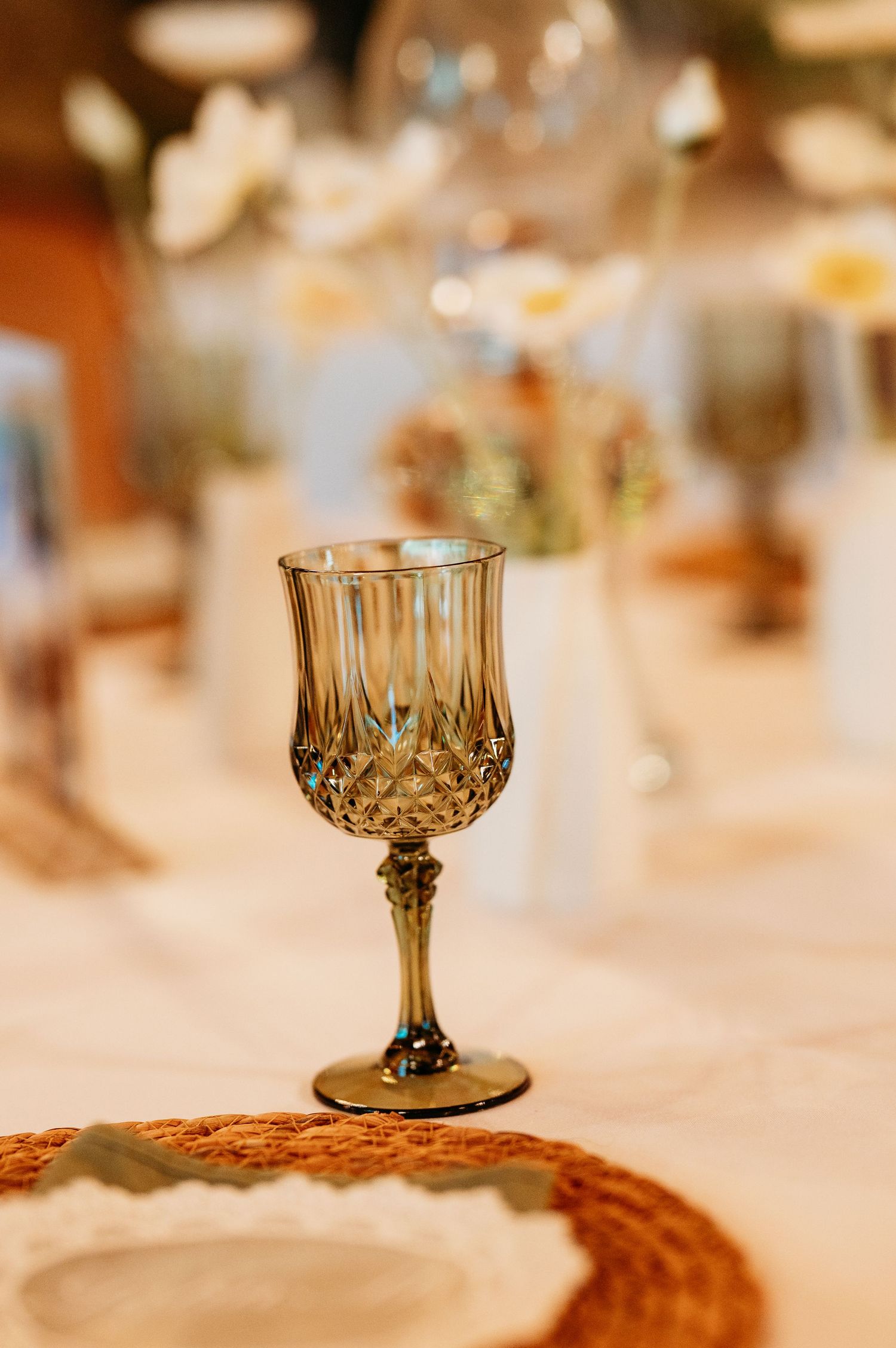 Elegant crystal goblet with intricate diamond pattern on a white tablecloth at a formal event.