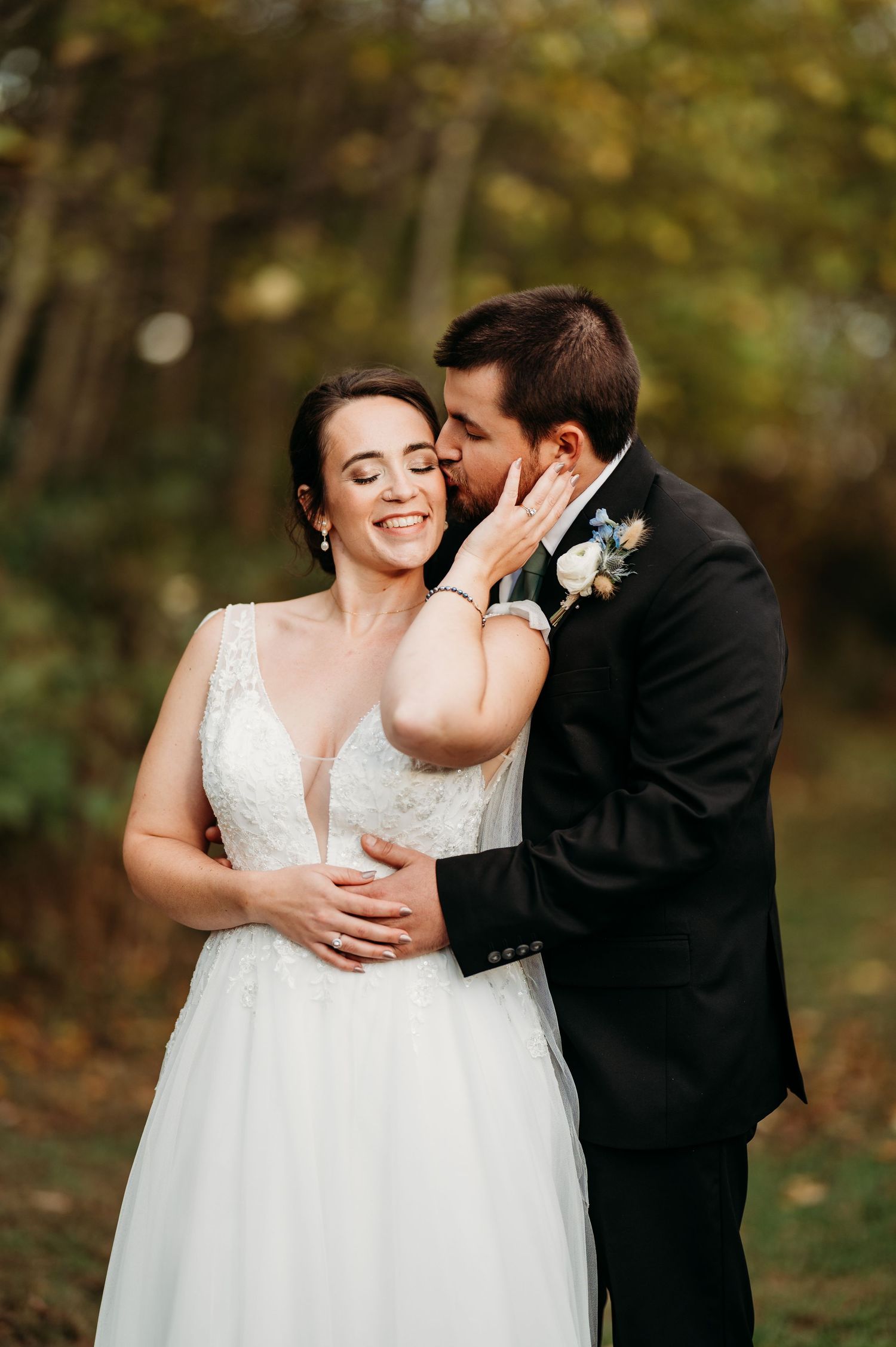 A couple shares an intimate moment during their outdoor autumn wedding celebration.