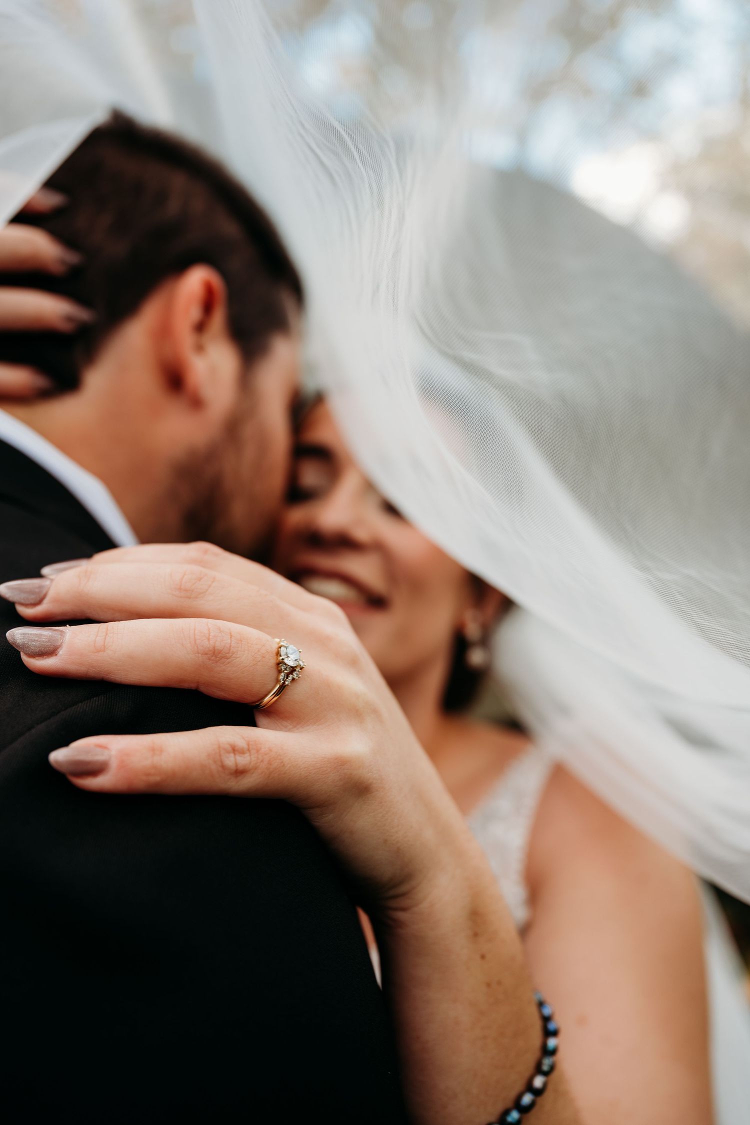 A romantic wedding moment captured in a series of close-up shots showing hands with rings and veils in soft lighting.