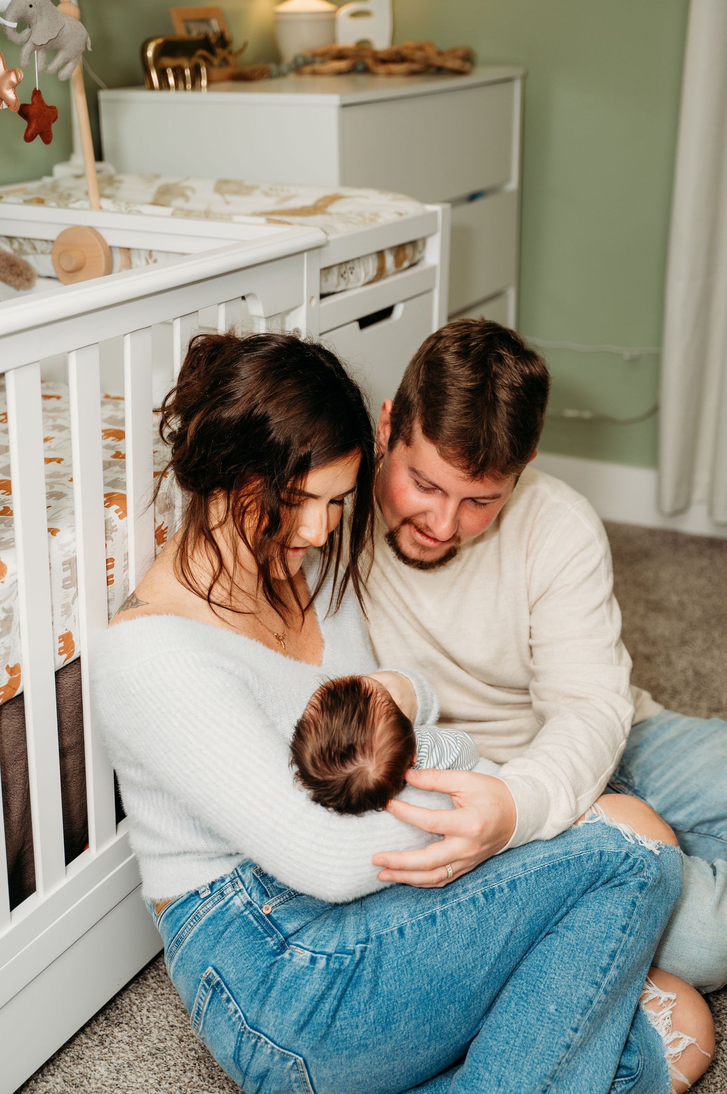 New parents sharing tender moment with baby near nursery crib.