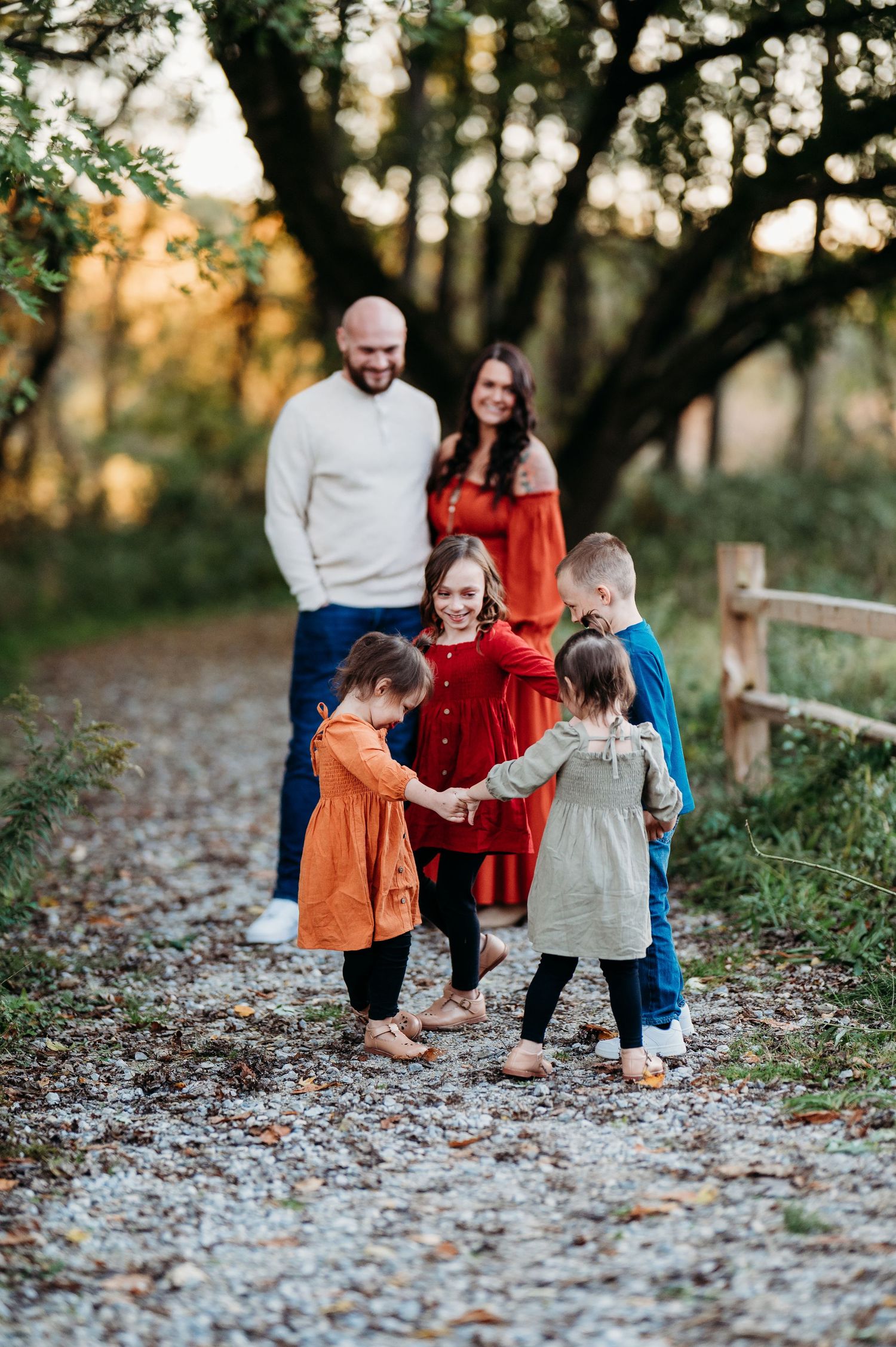 Family walking together on a leaf-covered path during golden hour in an autumn outdoor setting.