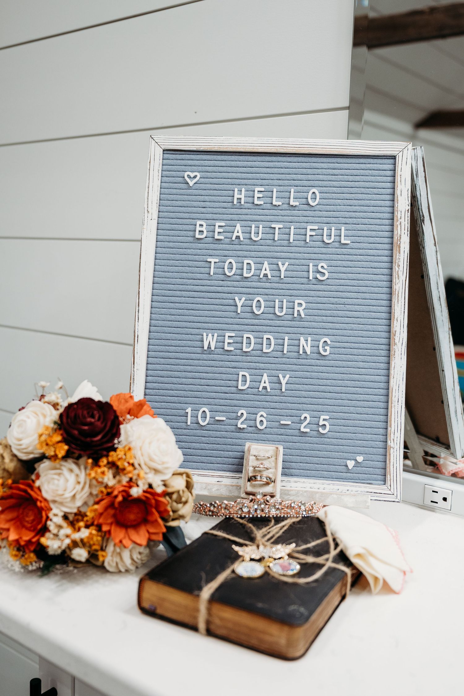 Letter board with wedding messages and floral decorations in autumn colors displayed with vintage books and decor elements.