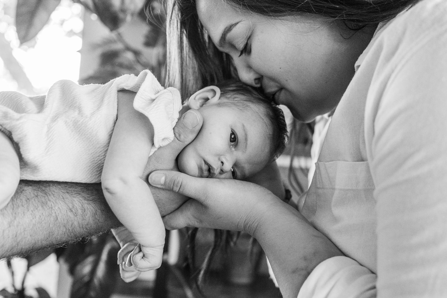 A series of tender moments showing a parent bonding with their newborn baby in black and white photographs.