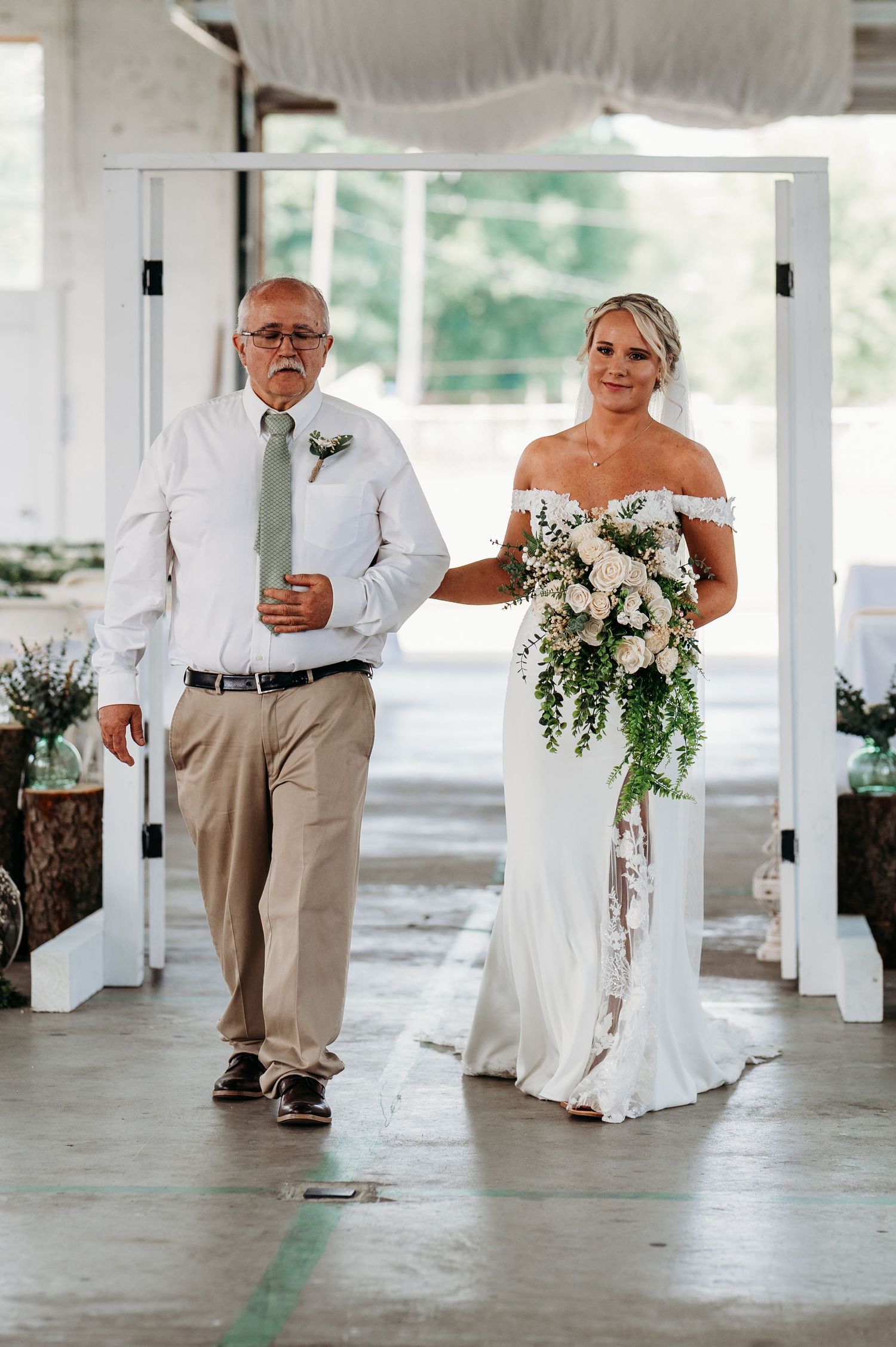 Wedding ceremony entrance with cascading floral bouquet and elegant white decor.