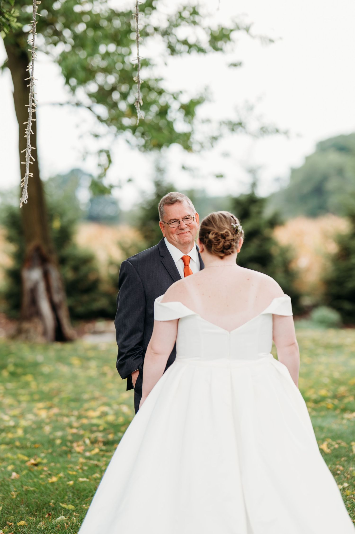 A wedding couple stands together on a grassy field dotted with yellow wildflowers.