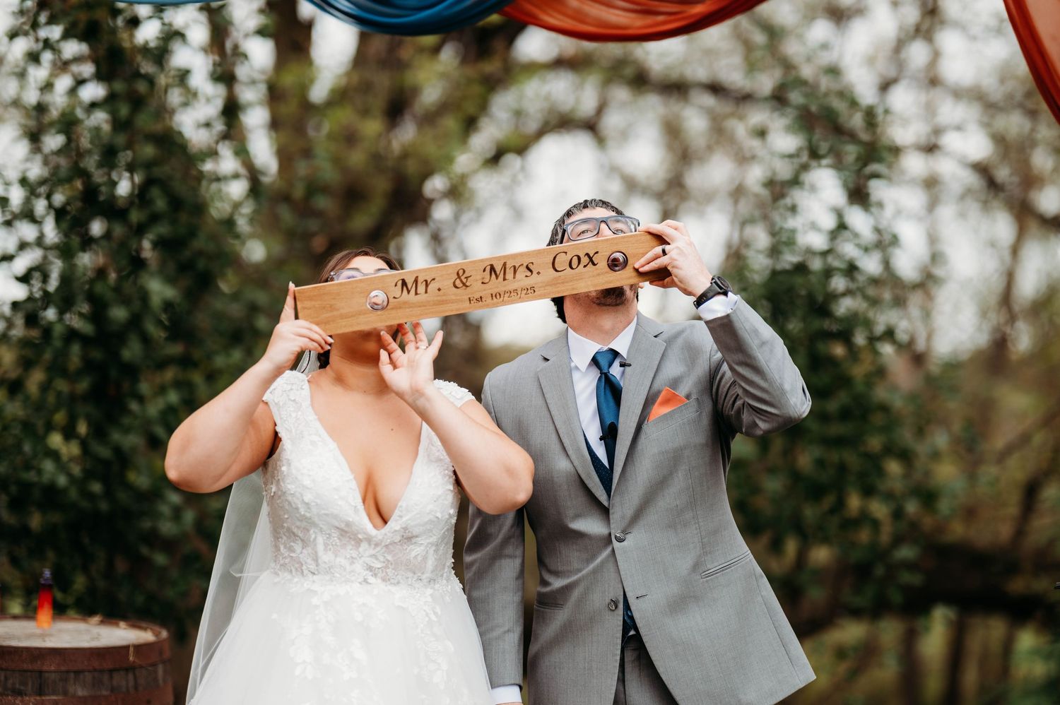 A romantic wedding couple shares an intimate kiss outdoors while holding champagne glasses during their celebration.