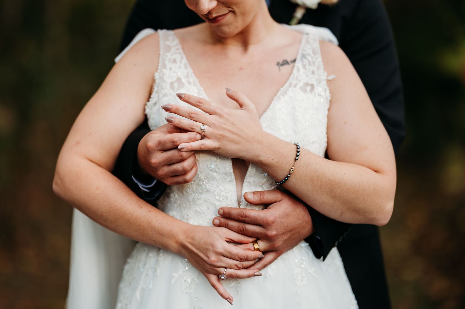 Close-up detail shot of a white lace wedding dress bodice with delicate beading and floral patterns.