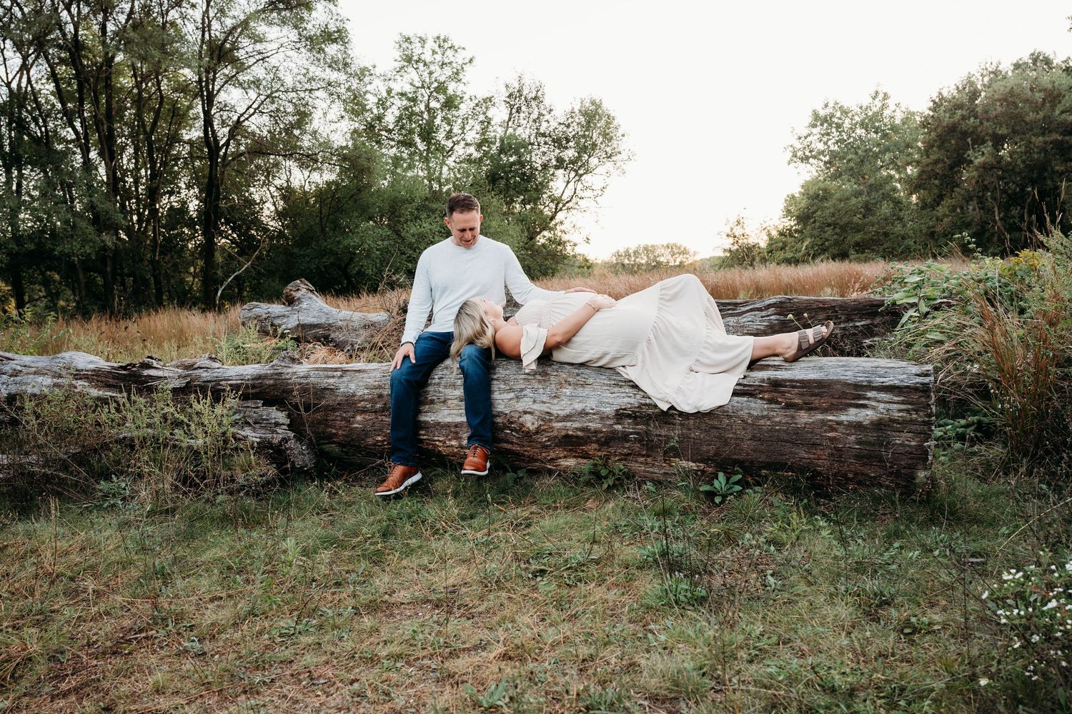 A romantic engagement photo session takes place on rocky terrain at sunset with natural lighting.