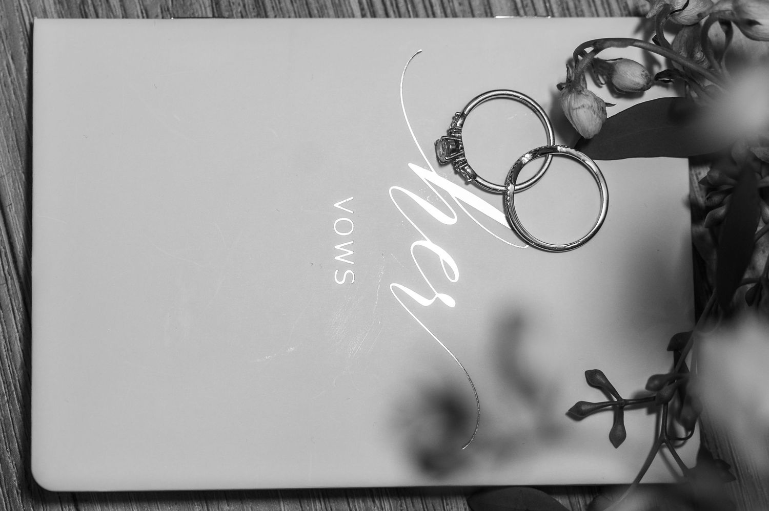 Wedding rings rest on a white Sony product card with soft shadow patterns in black and white photography.